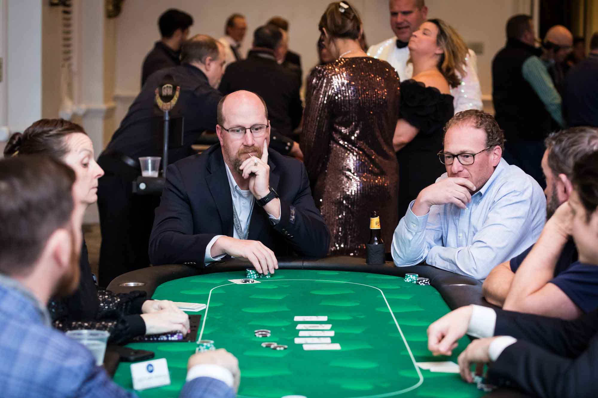 People looking at cards while sitting at a poker game table for an article on a St. Anthony Hotel corporate event