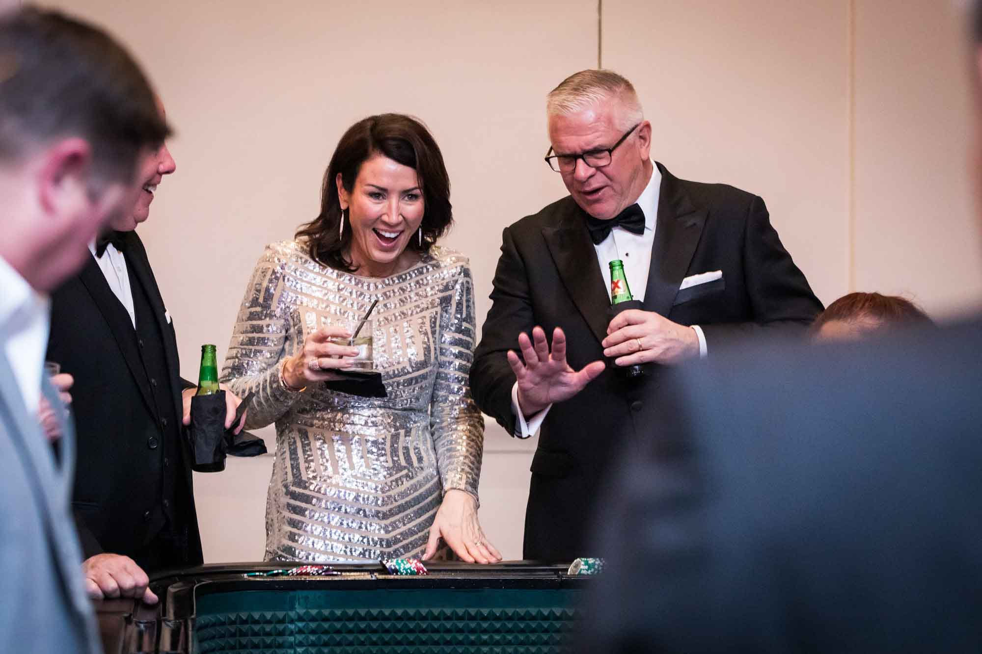Woman wearing silver sequin dress talking with man wearing black tuxedo for an article on a St. Anthony Hotel corporate event