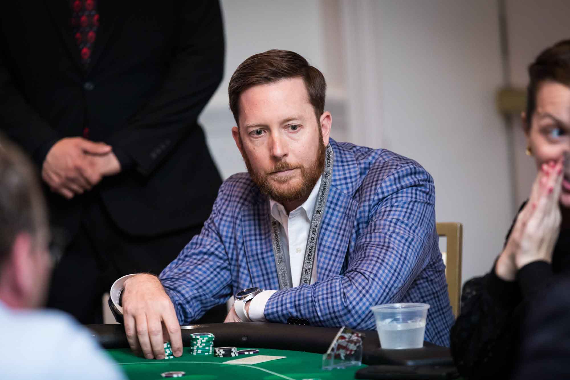 Man wearing blue checkered blazer holding poker chips at a game table for an article on a St. Anthony Hotel corporate event