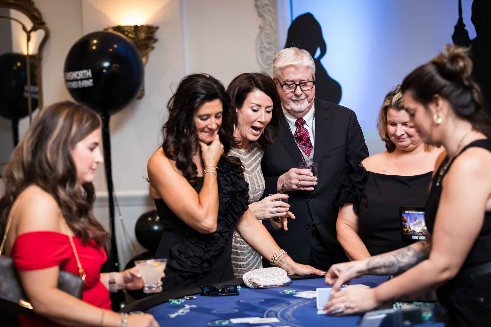 Guests enjoying watching a dealer flip cards at a card table for an article on a St. Anthony Hotel corporate event