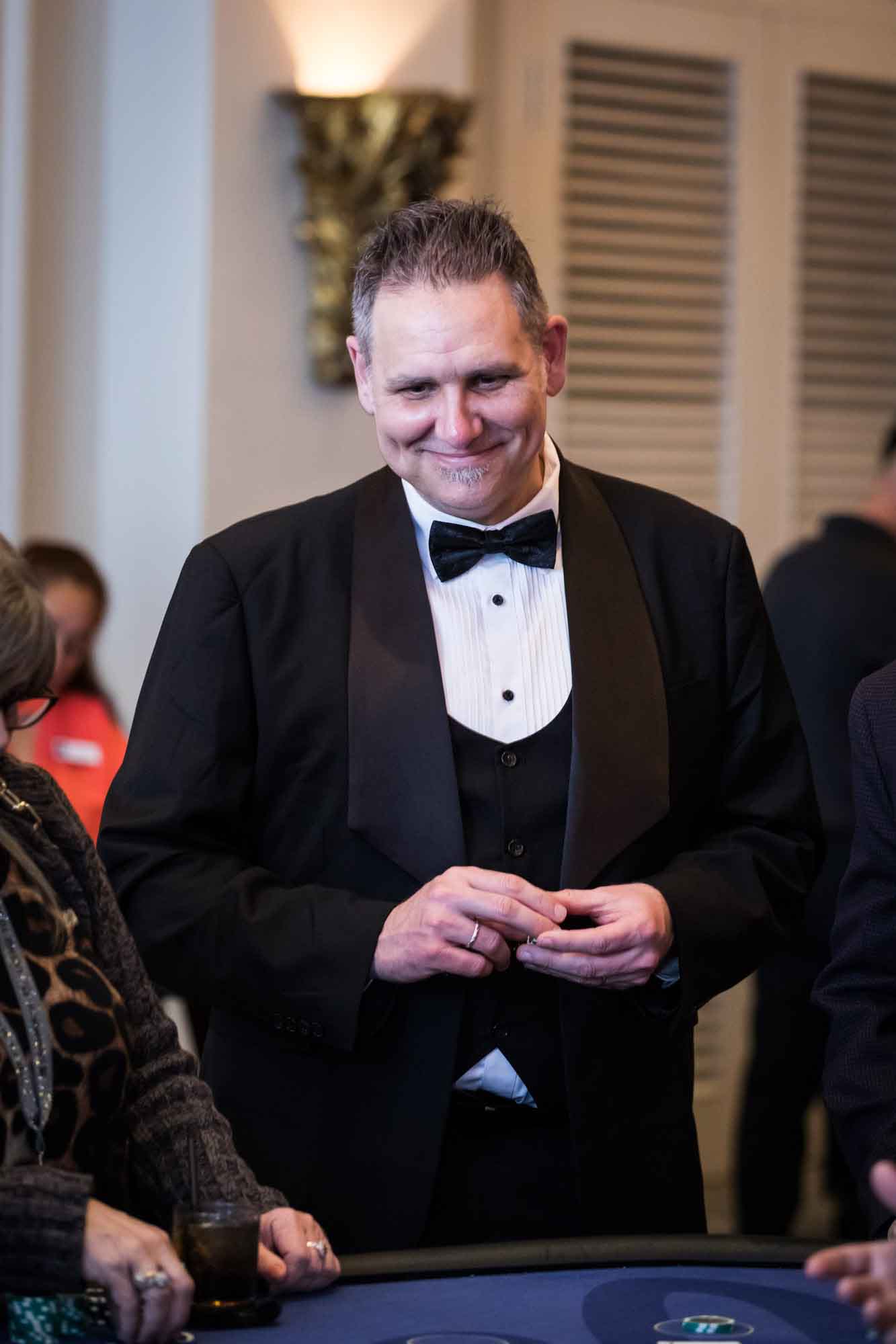 Man wearing a tuxedo with bow tie holding chips at a card table for an article on a St. Anthony Hotel corporate event