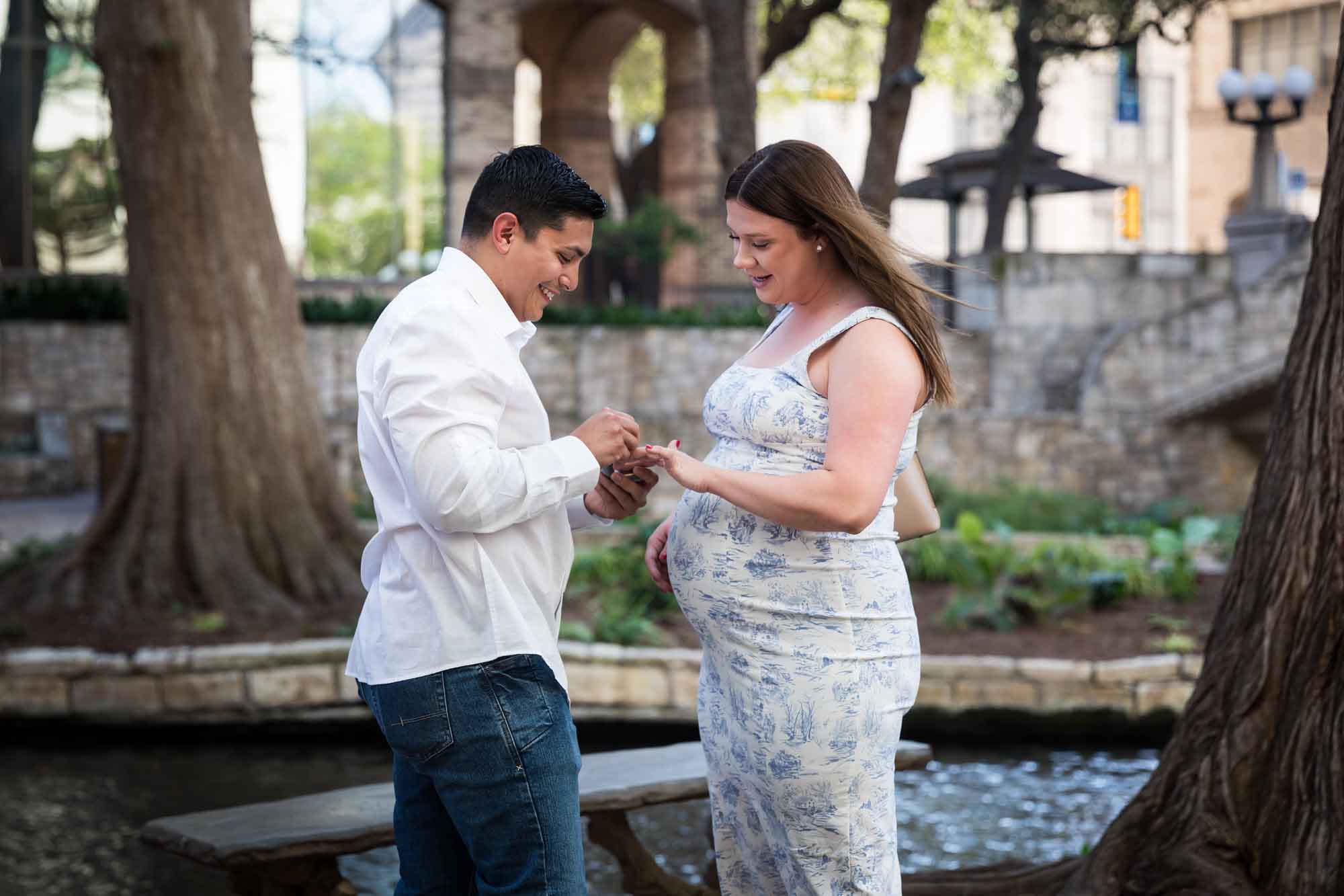 Man putting engagement ring on pregnant fiancee's finger during Marriage Island proposal for an article on the best place to propose on the River Walk