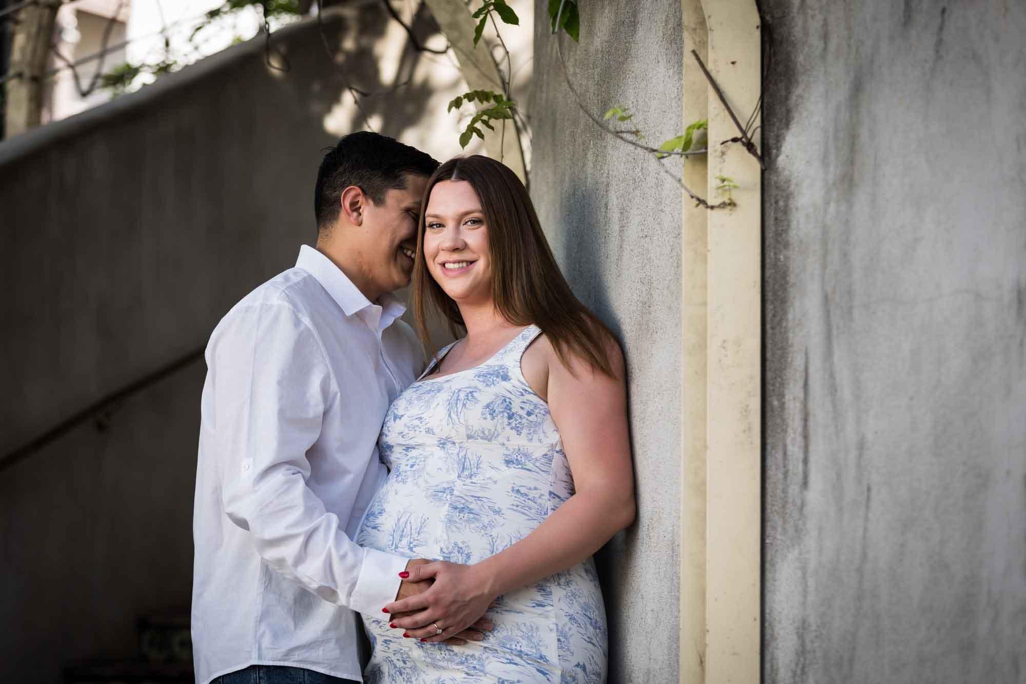 Pregnant couple standing against mosaic staircase during a La Villita engagement portrait session
