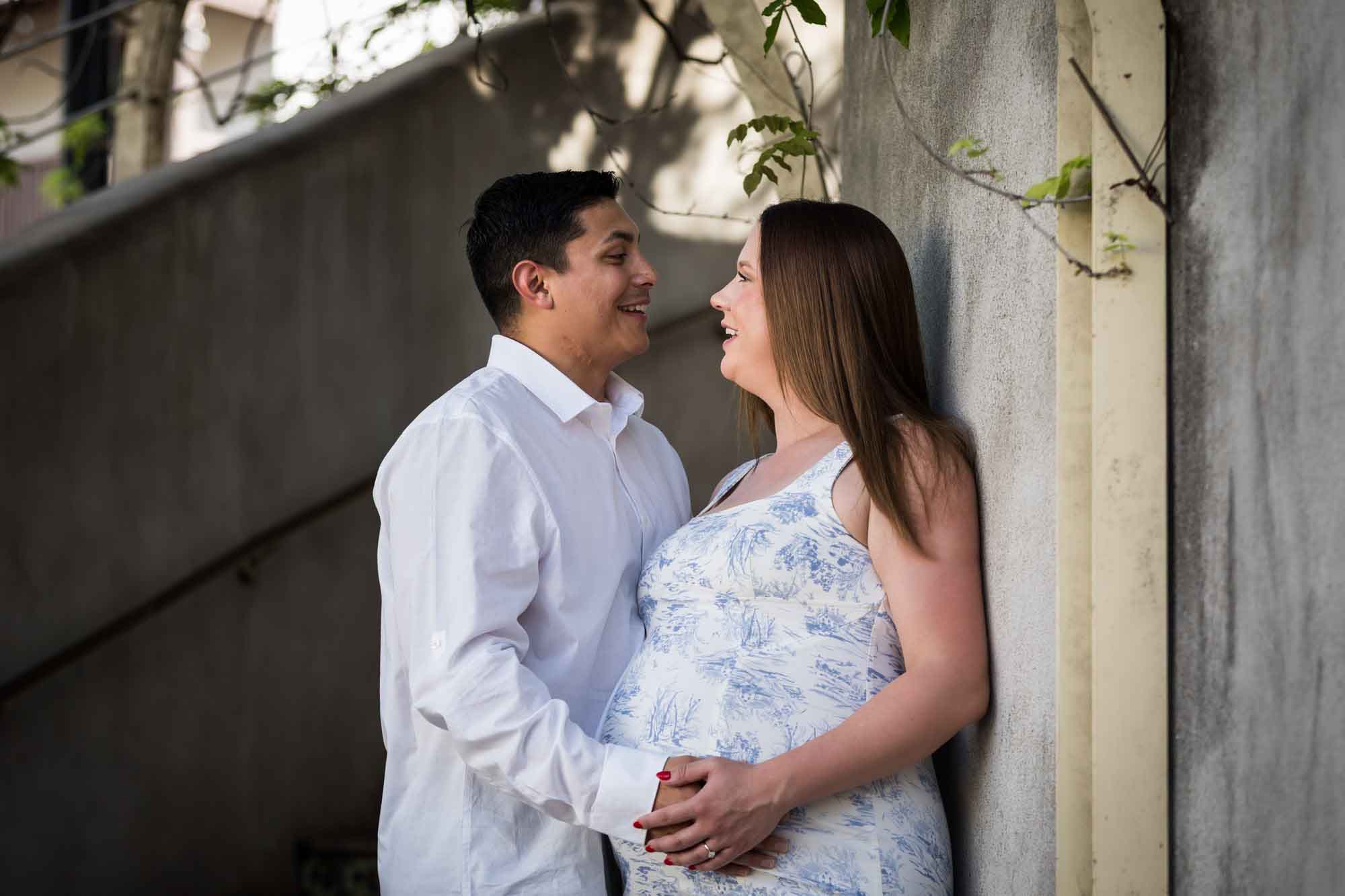 Pregnant couple standing against mosaic staircase during a La Villita engagement portrait session