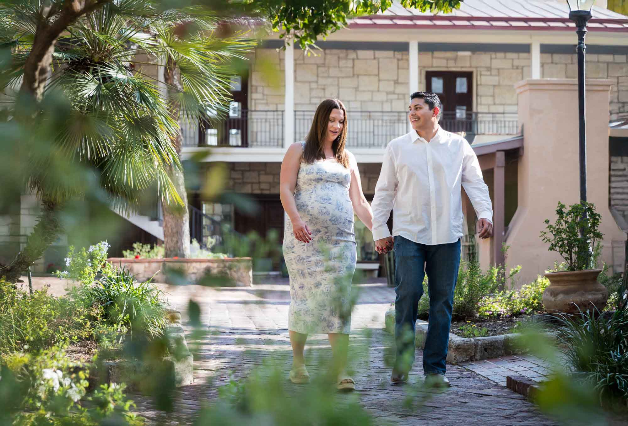 Pregnant couple walking down pathway during a La Villita engagement portrait session