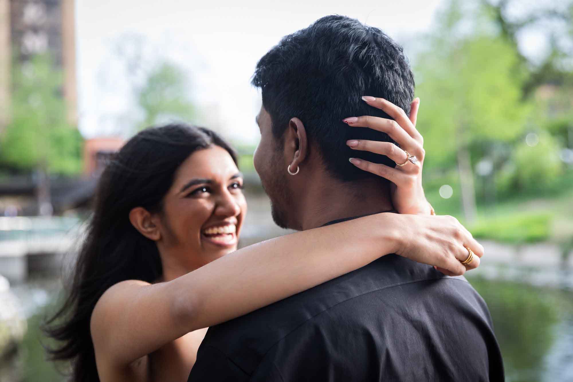 Woman hugging man showing engagement ring on her finger for an article on where hide the engagement ring box before the proposal