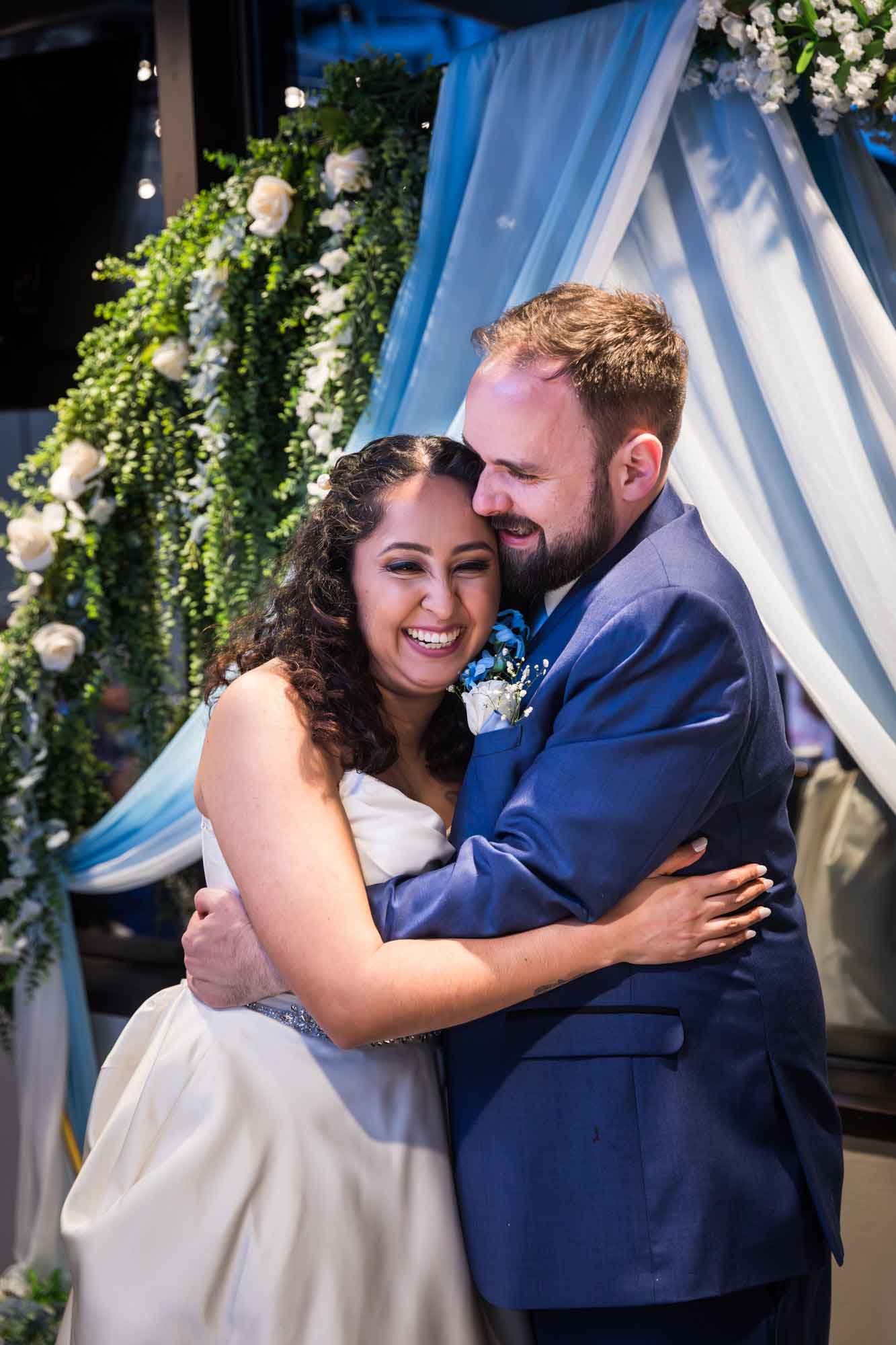Centre Club wedding reception photo of bride and groom hugging in front of flower arch