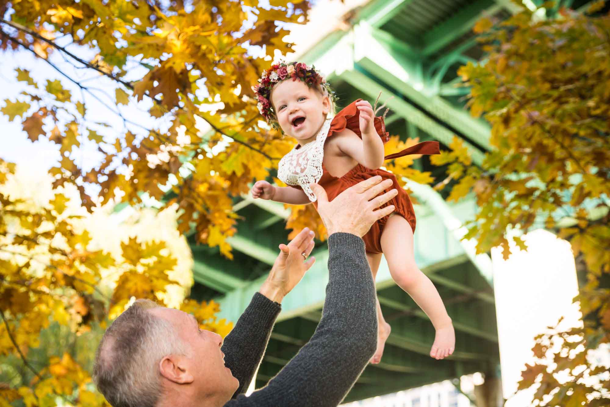 Father throwing little girl up in the air in Riverside Park