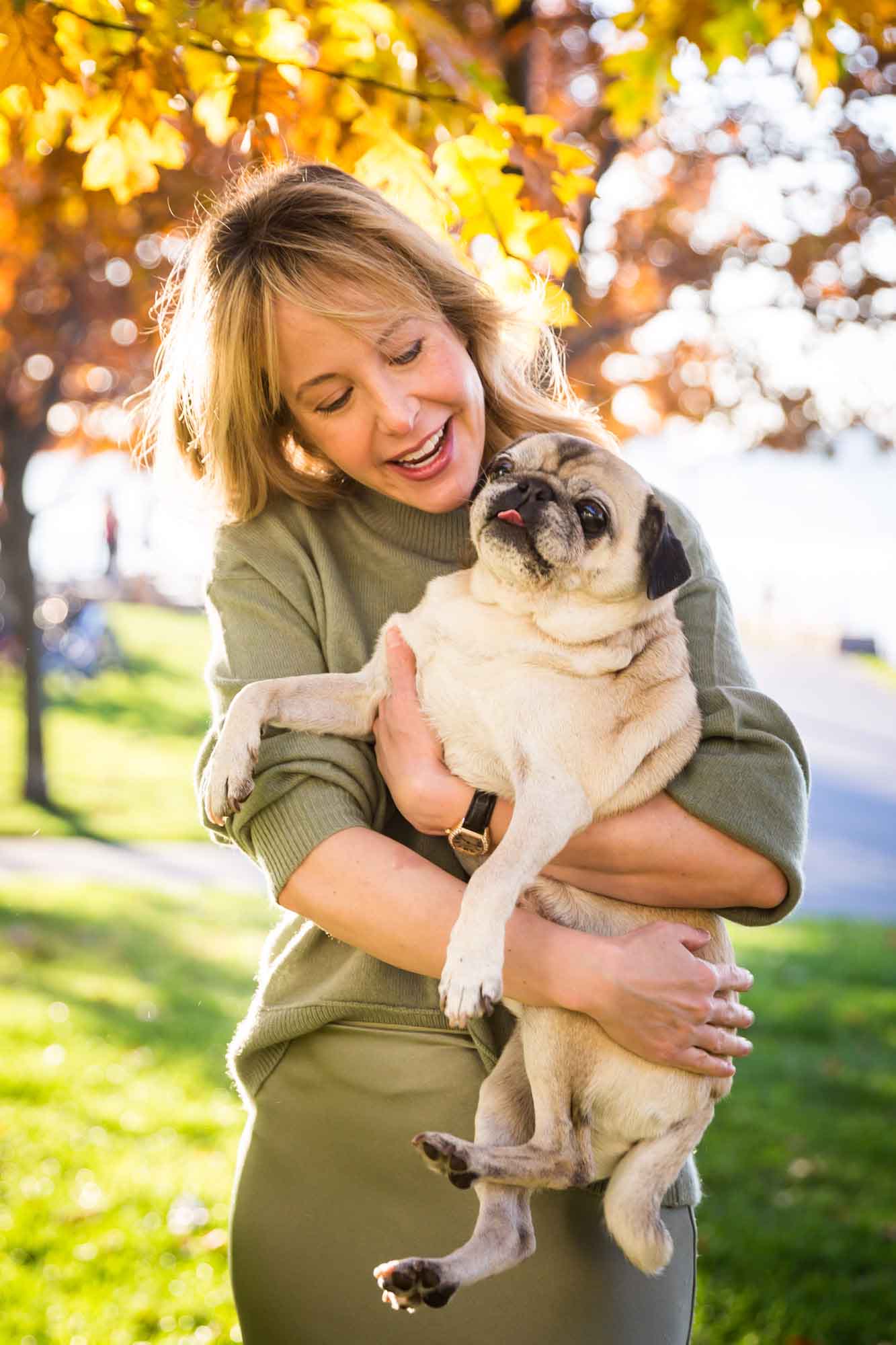 Mother holding pug dog during golden hour