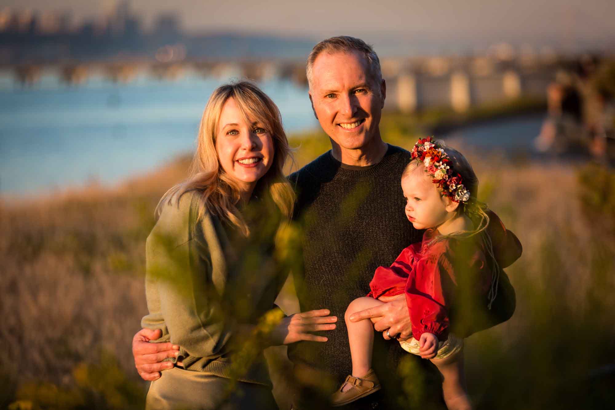 Parents holding little girl in Riverside Park Mother showing leaf to baby girl for an article NYC golden hour portrait tips