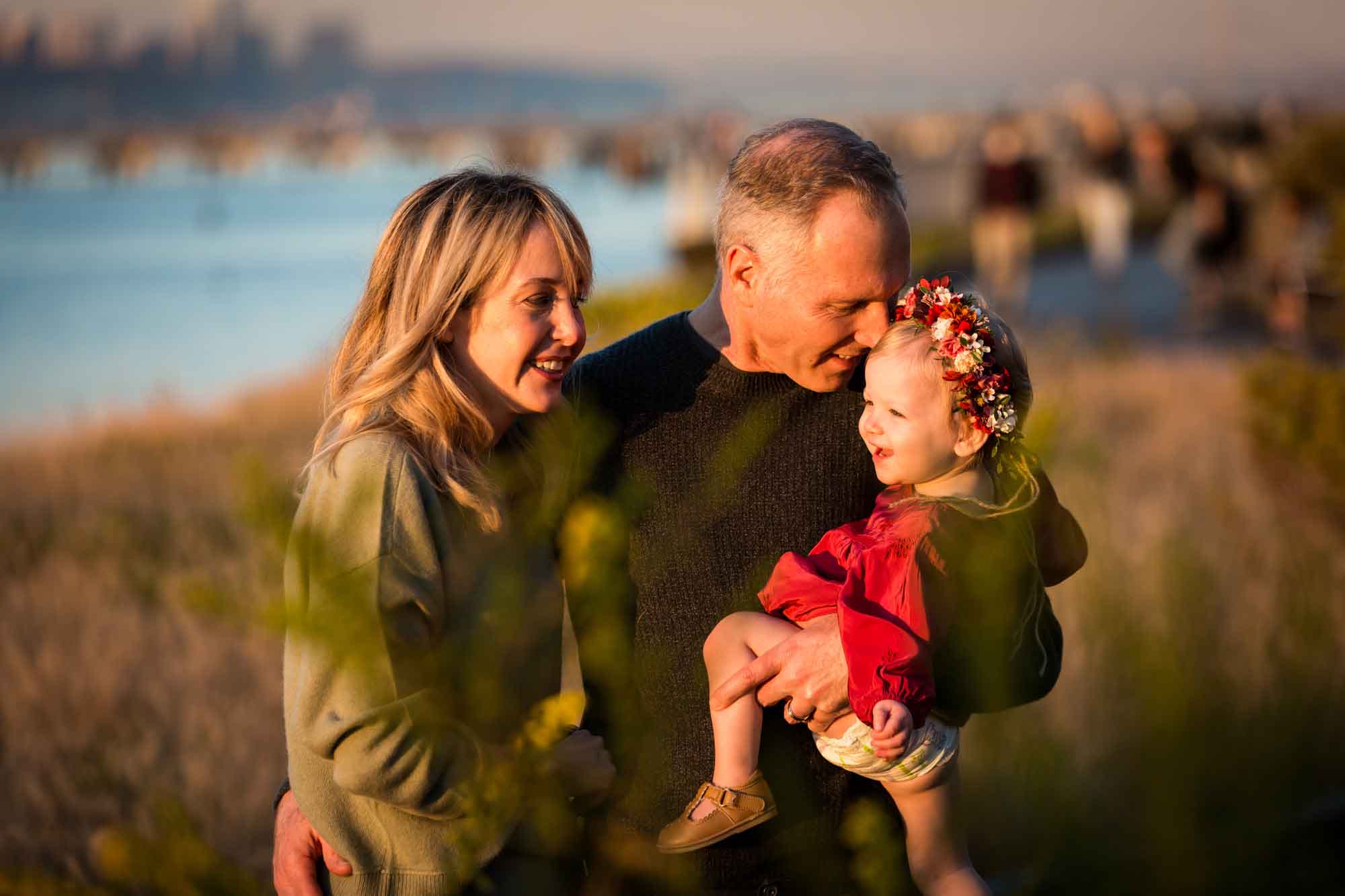 Parents watching little girl in Riverside Park during golden hour