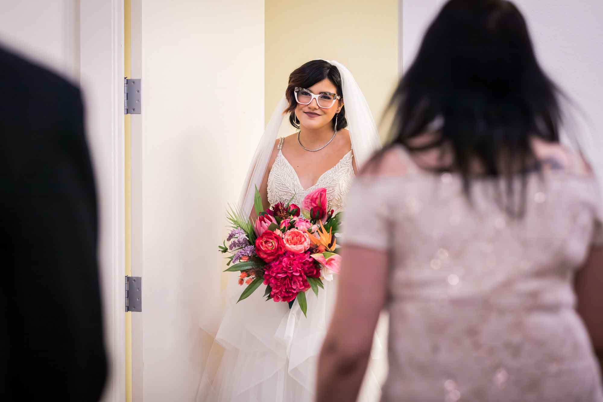 Cornerstone Church wedding photos of bride holding large flower bouquet looking out doorway at two guests