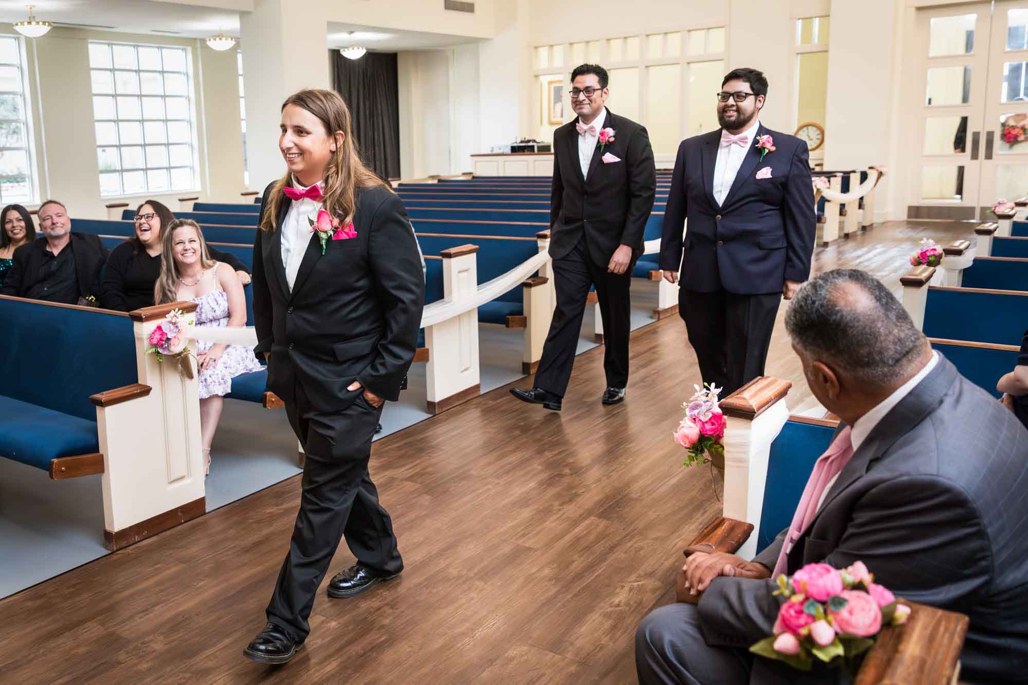 Cornerstone Church wedding photos of groom and two groomsmen walking down aisle in front of guests during ceremony