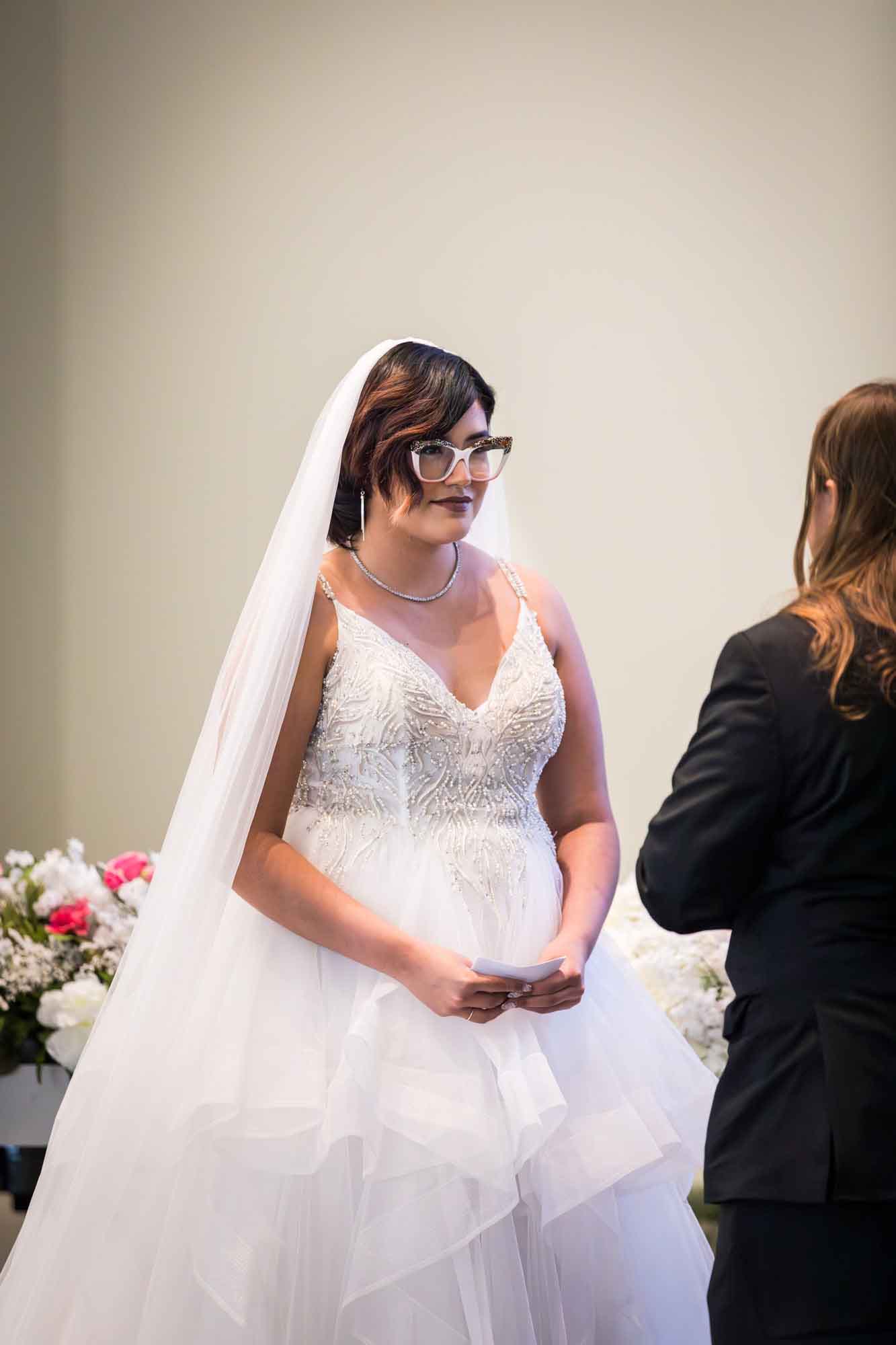 Cornerstone Church wedding photos of bride wearing sleeveless white dress and long veil holding white piece of paper in front of groom