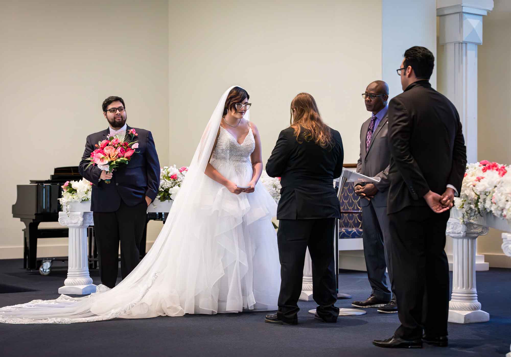 Cornerstone Church wedding photos of bride and groom saying vows to each other in front of officiant and two groomsmen during ceremony