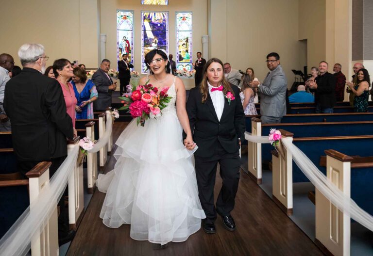 Cornerstone Church wedding photos of bride and groom walking down aisle with guests clapping in pews