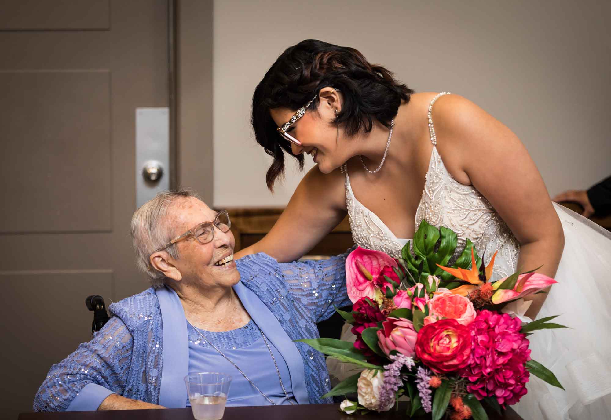 Bride holding large flower bouquet smiling and greeting older woman wearing lavender dress at Cornerstone Church