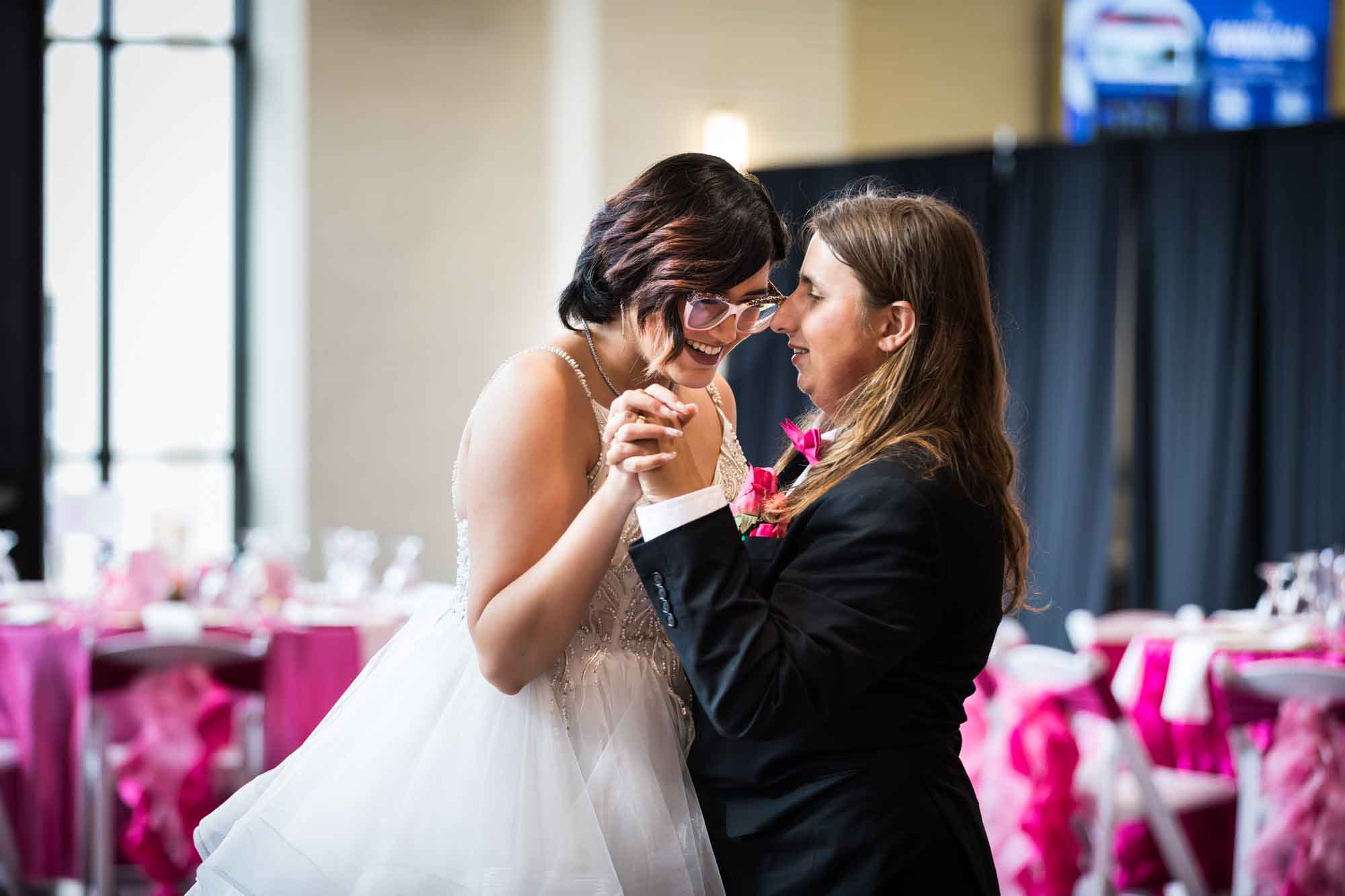Bride and groom dancing close in front of tables with pink tablecloths at Cornerstone Church