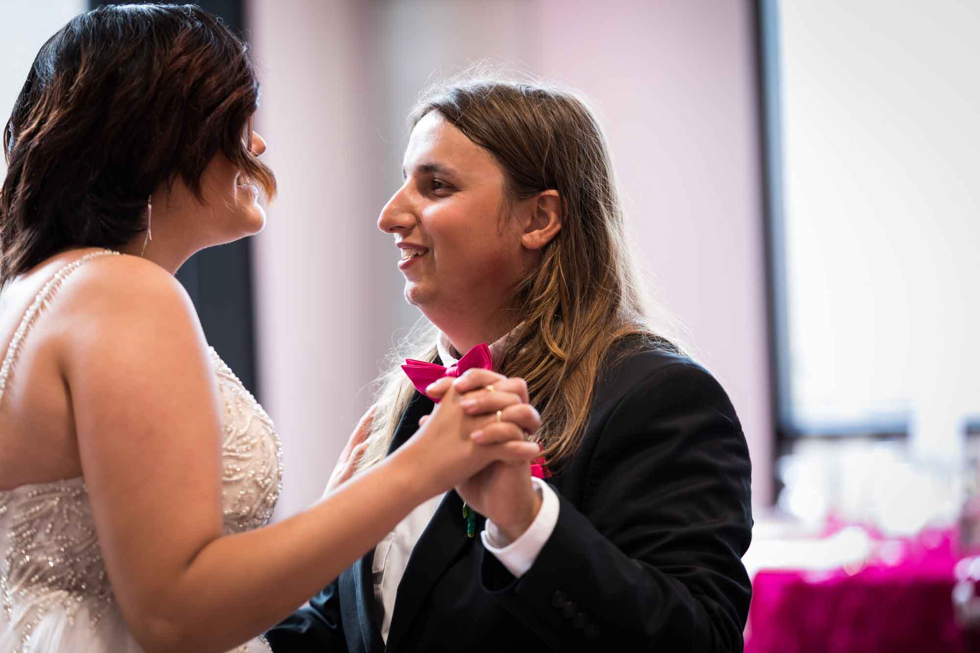 Bride and groom dancing close in front of tables with pink tablecloths at Cornerstone Church
