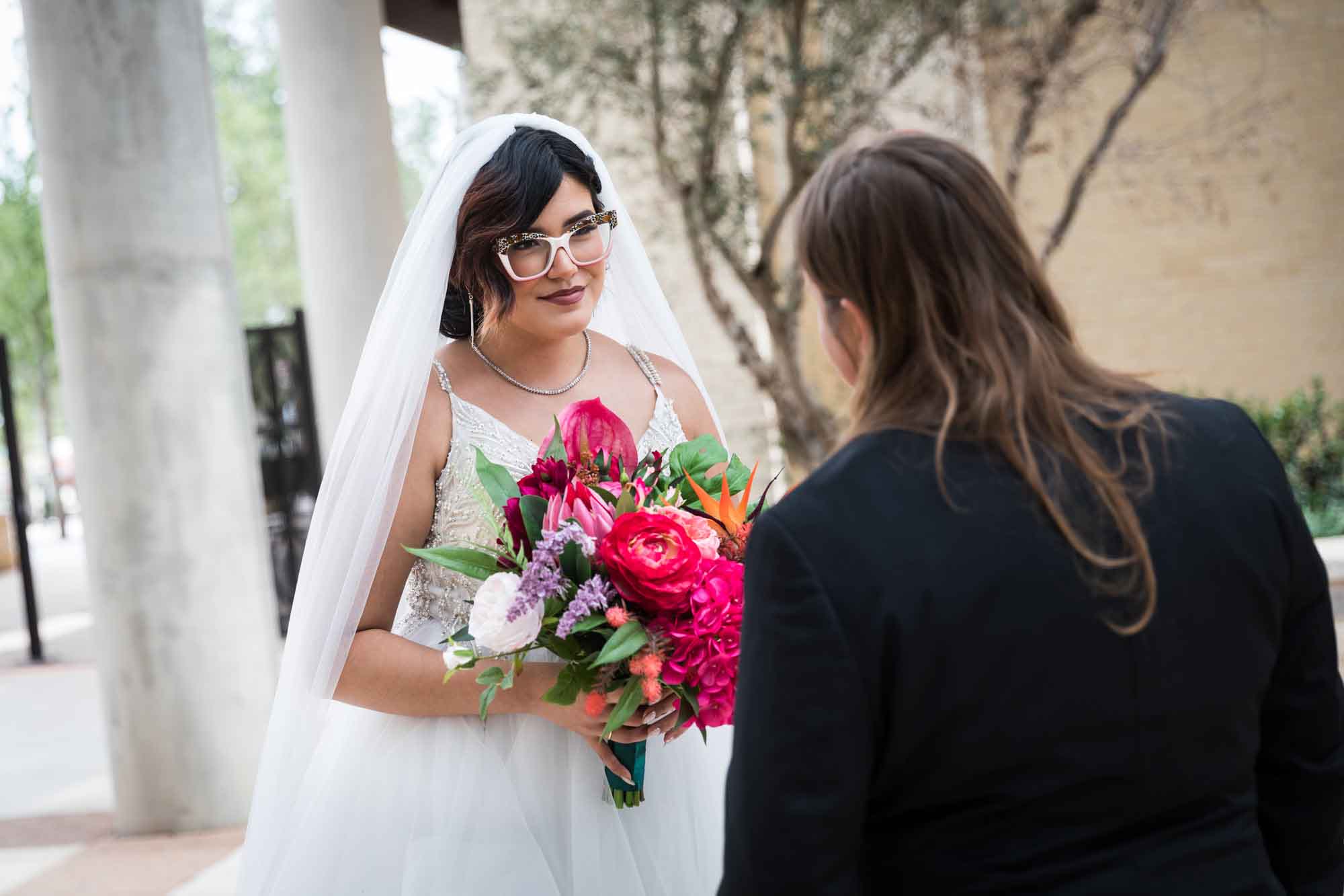 Cornerstone Church wedding photos of bride wearing veil and holding flower bouquet looking at groom with long hair