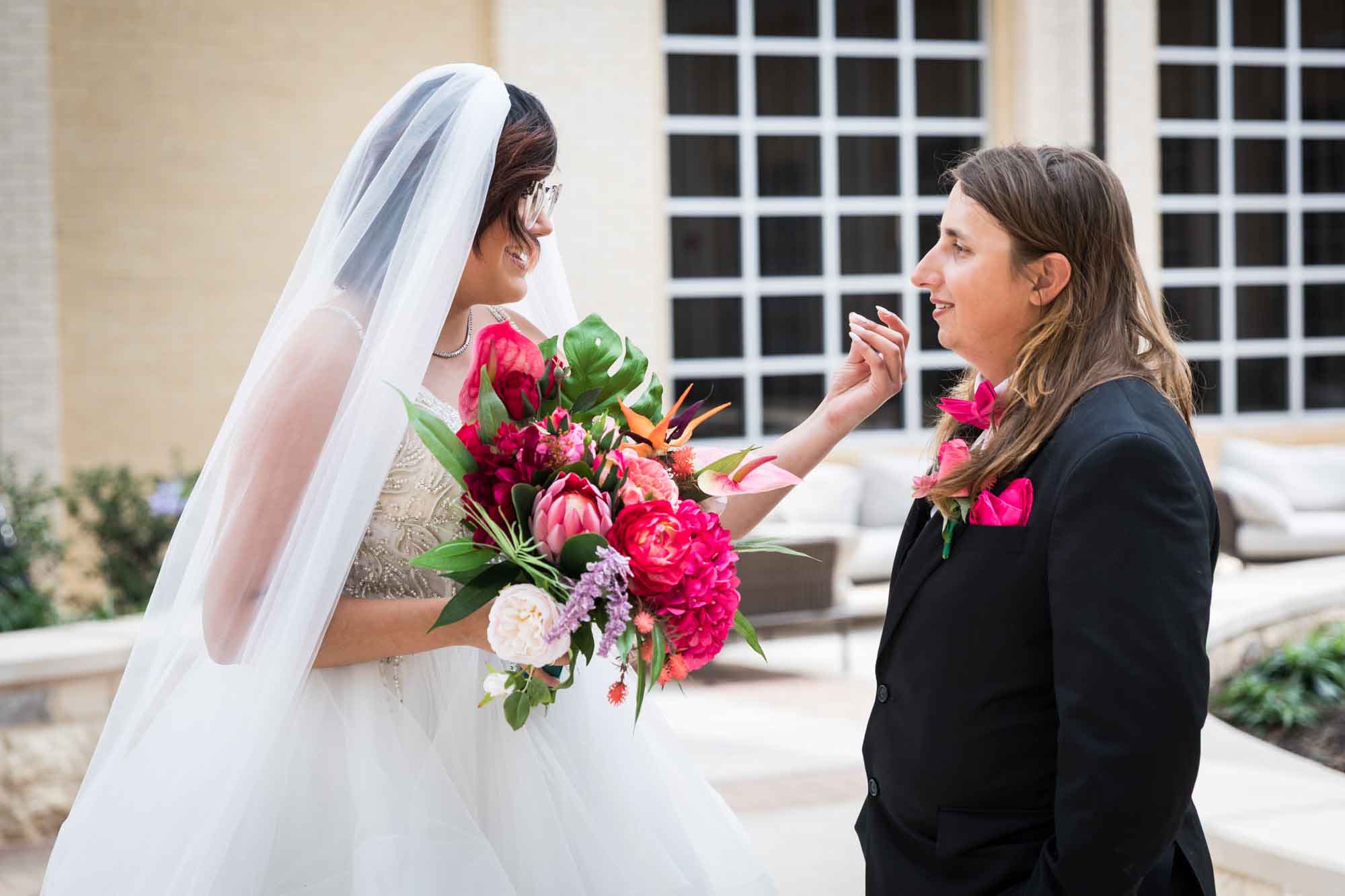 Cornerstone Church wedding photos of bride wearing veil and holding large flower bouquet about to touch groom's face with hand