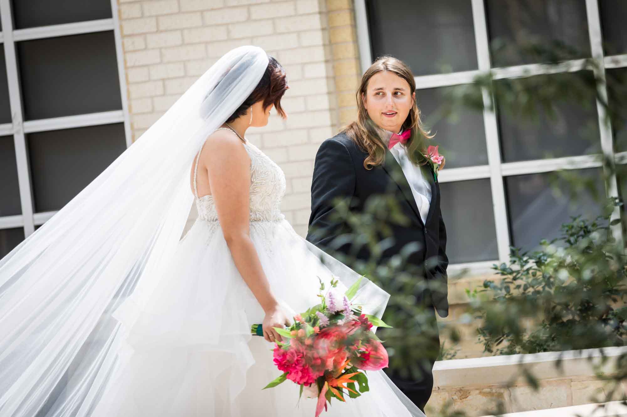 Cornerstone Church wedding photos of bride wearing sleeveless dress and holding flower bouquet holding hands with groom while walking in courtyard