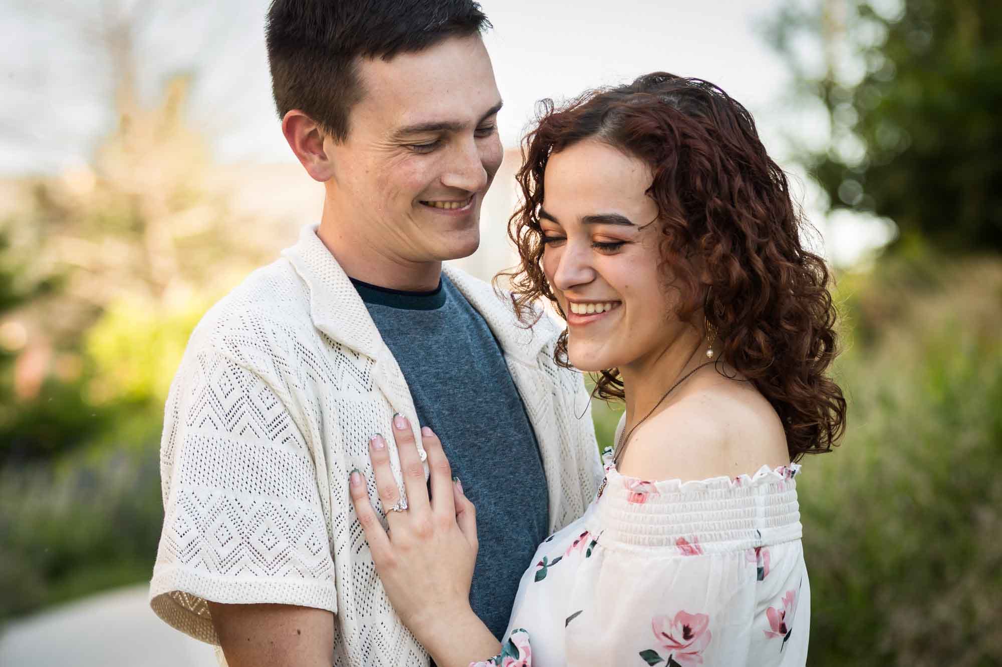 Downtown San Antonio engagement photos of couple laughing with woman's hand on man's chest in San Pedro Creek Park