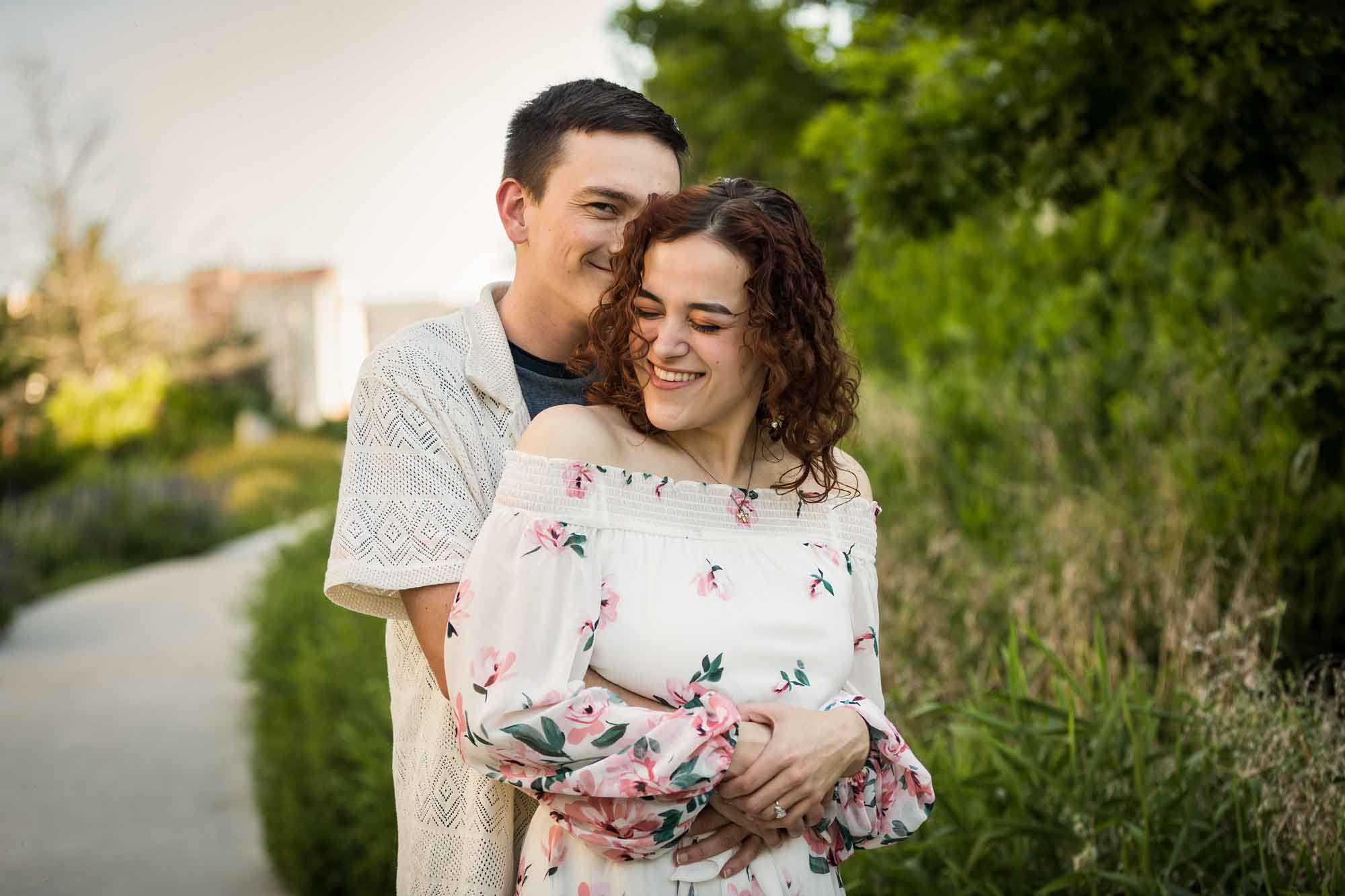 Downtown San Antonio engagement photos of couple hugging in front of green bushes in San Pedro Creek Park