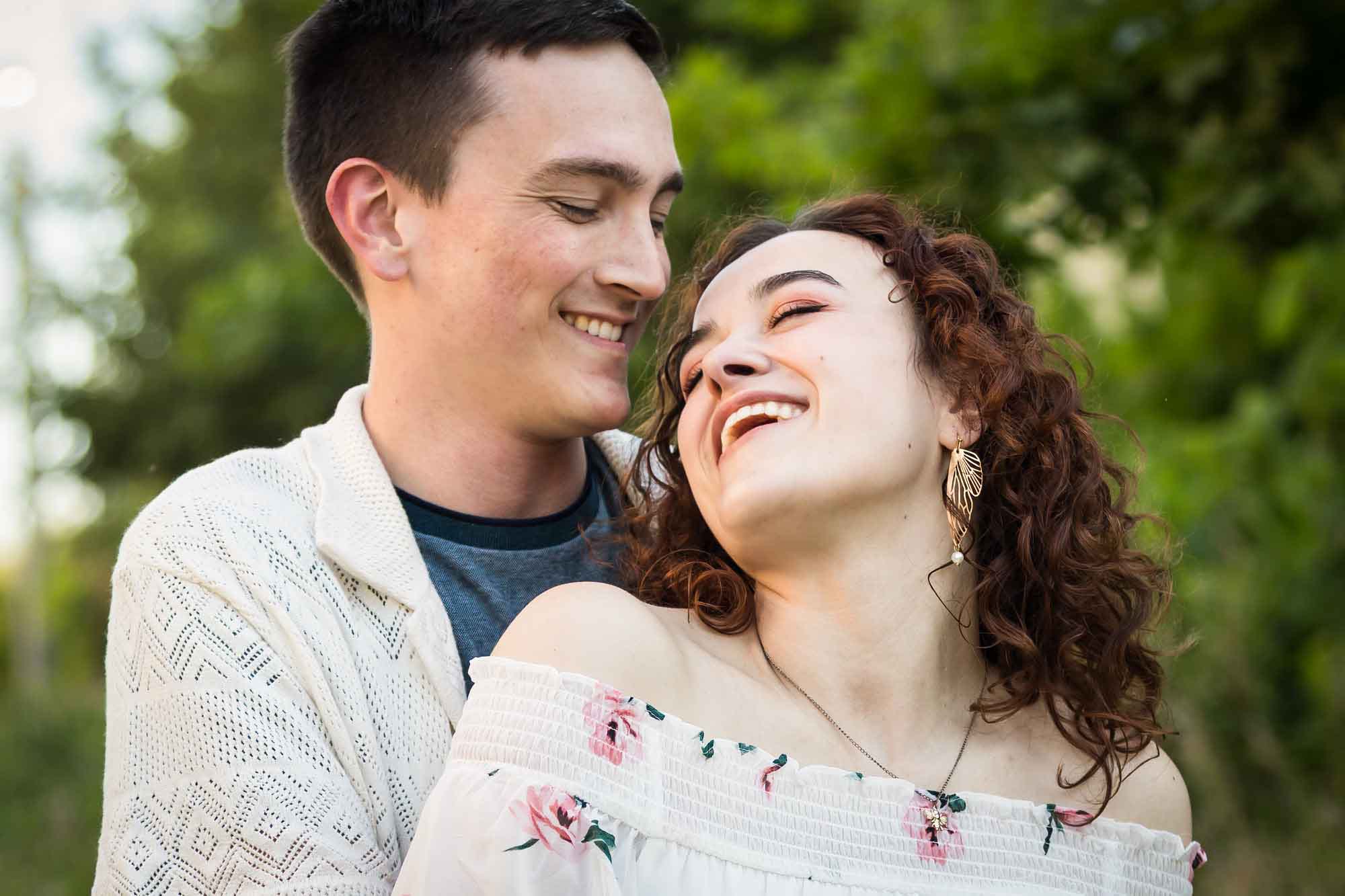 Downtown San Antonio engagement photos of couple laughing in front of green bushes in San Pedro Creek Park