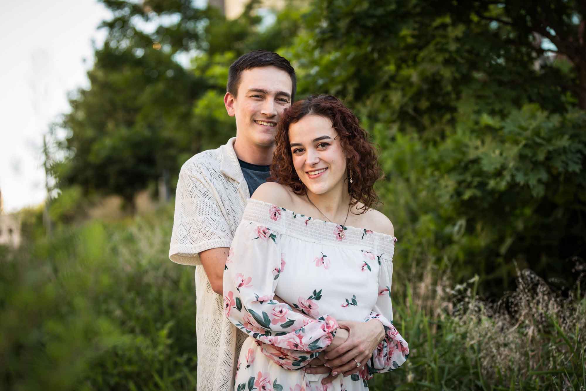 Downtown San Antonio engagement photos of couple hugging in front of green bushes in San Pedro Creek Park