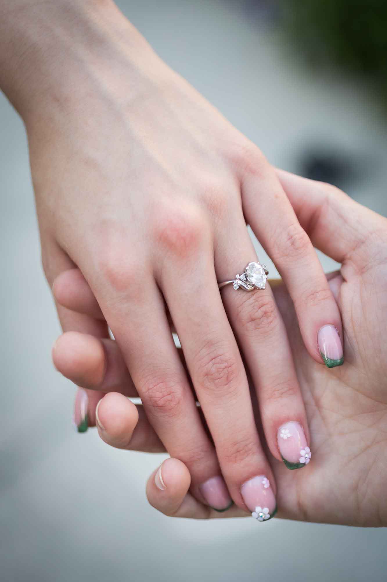 Close up of man holding woman's hand showing engagement ring