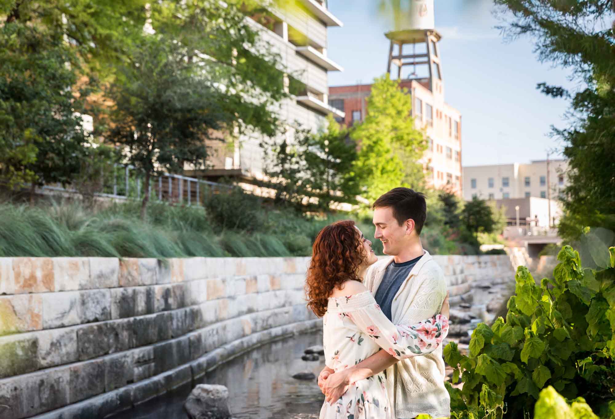 Downtown San Antonio engagement photos of couple hugging in front of brick wall in San Pedro Creek Park