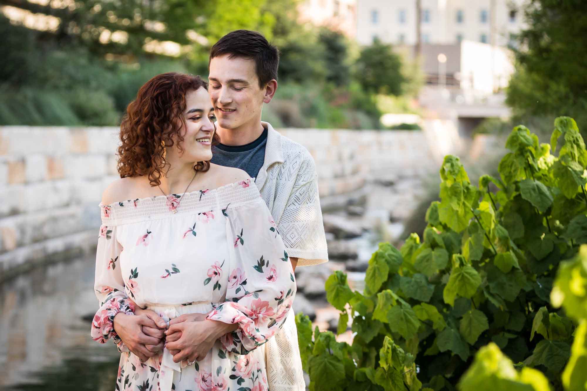 Downtown San Antonio engagement photos of couple hugging in front of brick wall in San Pedro Creek Park