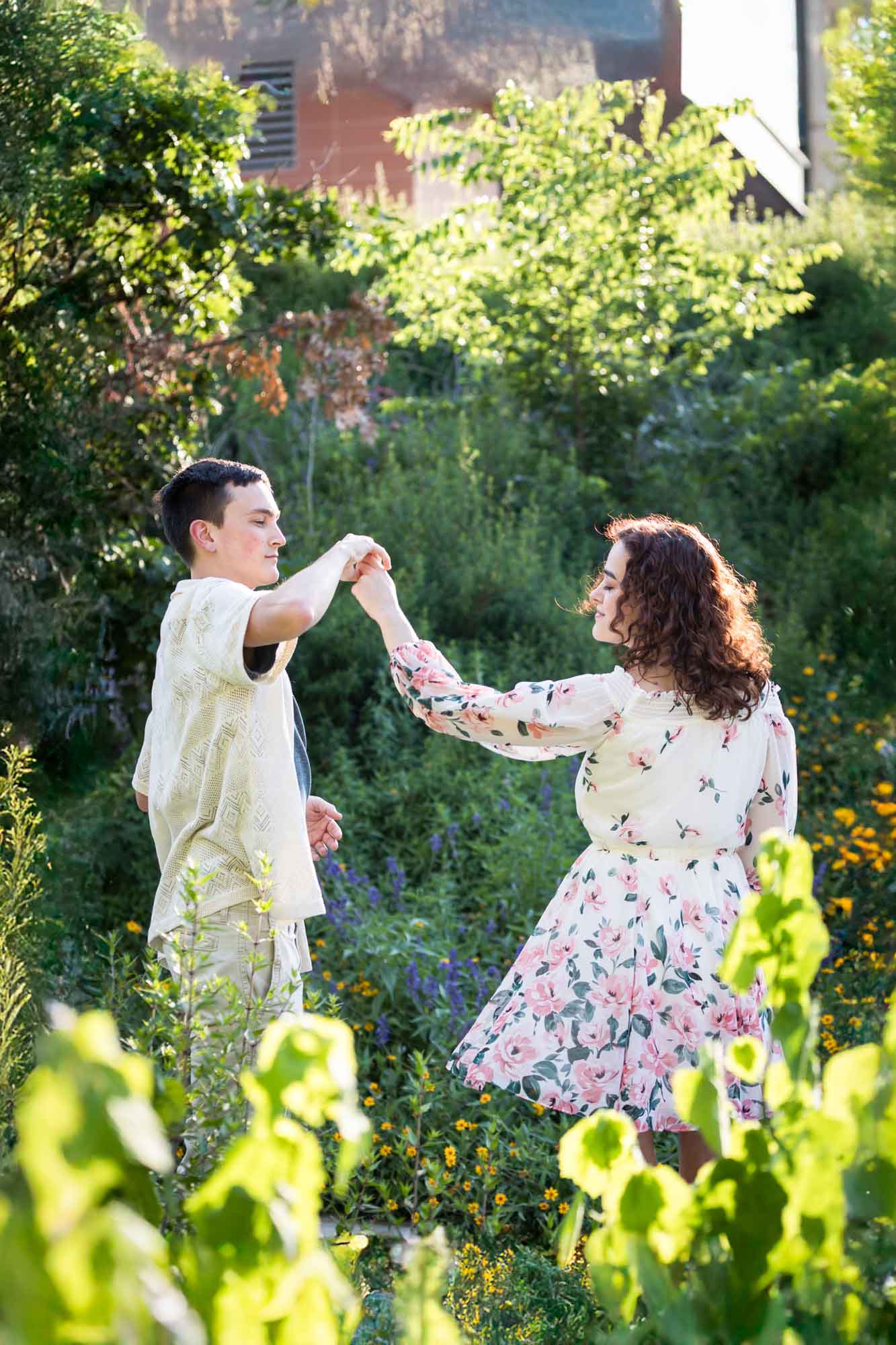 Downtown San Antonio engagement photos of couple dancing together in front of green bushes in San Pedro Creek Park