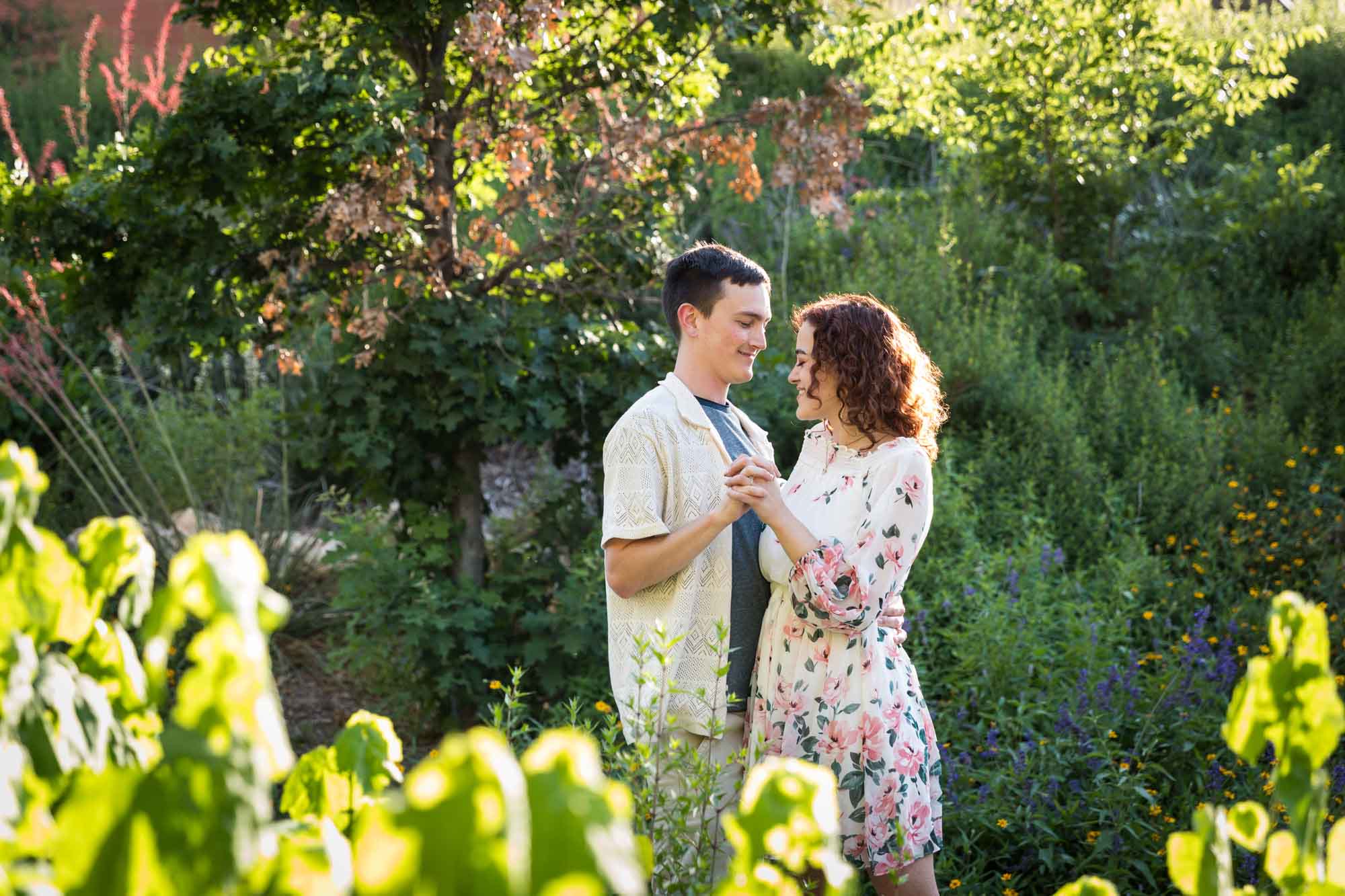 Downtown San Antonio engagement photos of couple dancing together in front of green bushes in San Pedro Creek Park