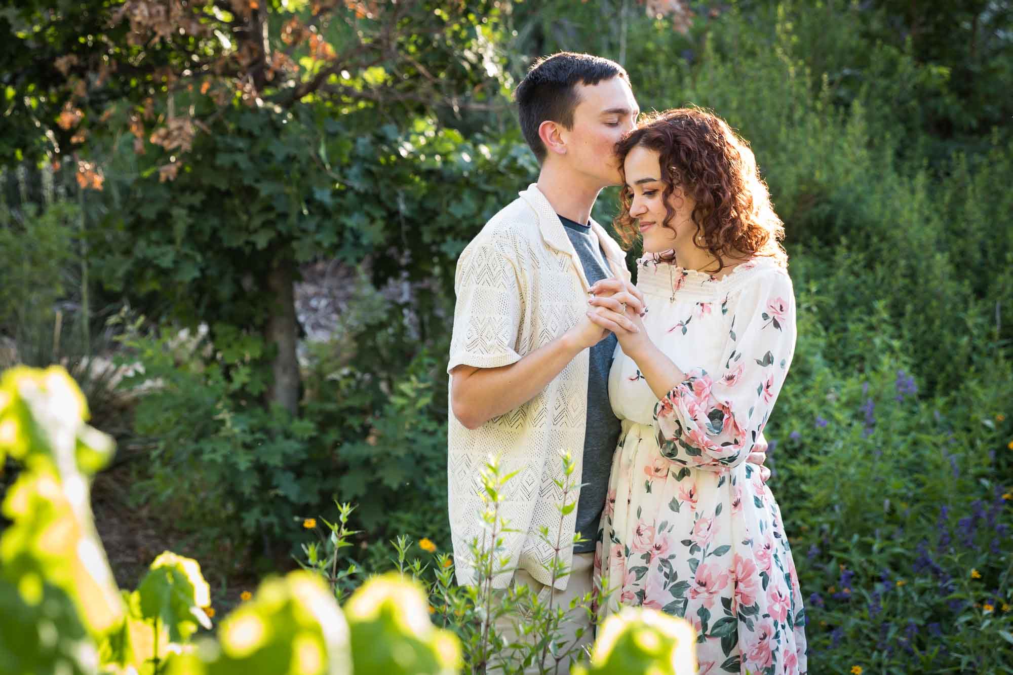 Downtown San Antonio engagement photos of couple dancing together in front of green bushes in San Pedro Creek Park