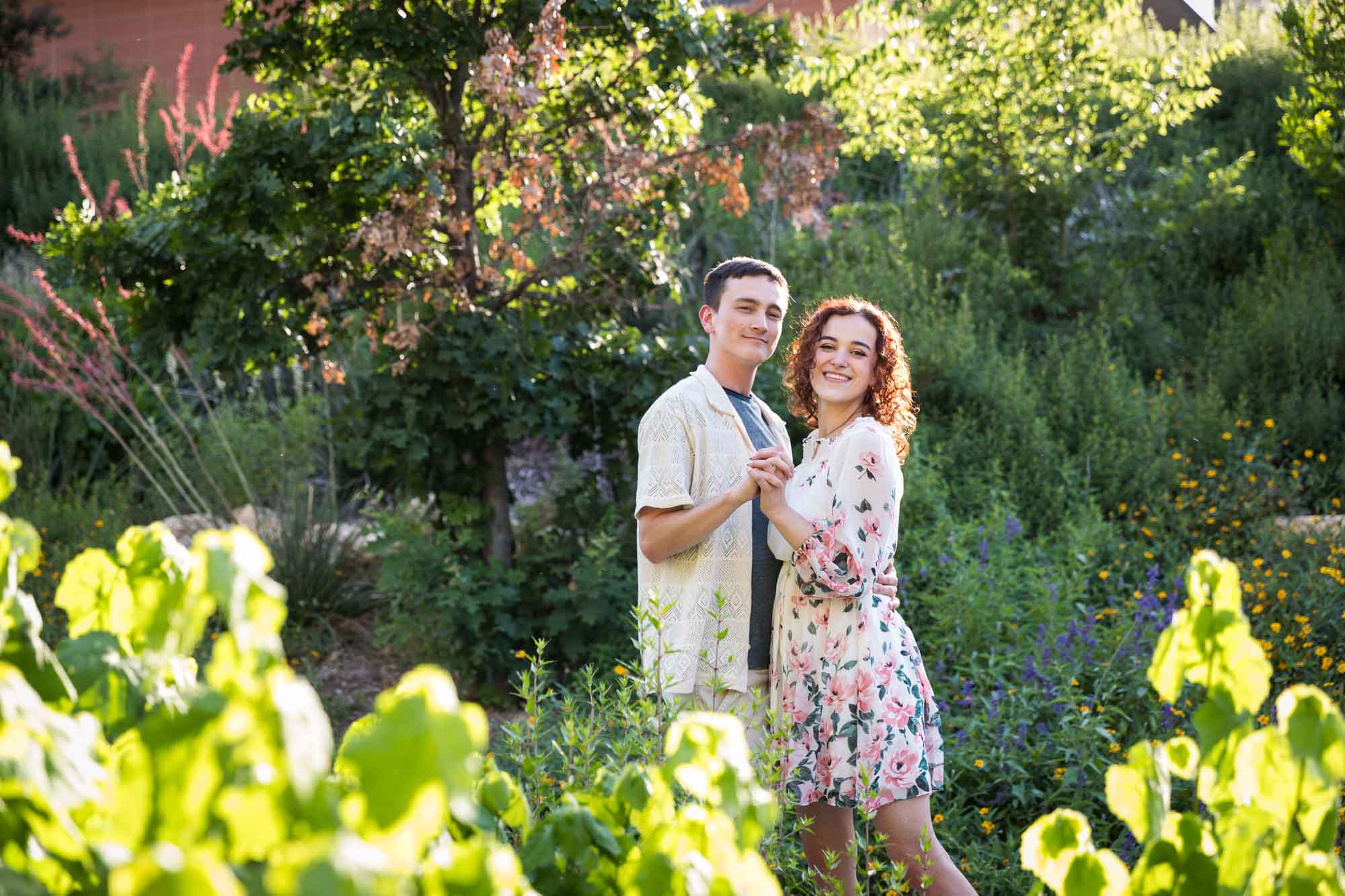 Downtown San Antonio engagement photos of couple dancing together in front of green bushes in San Pedro Creek Park