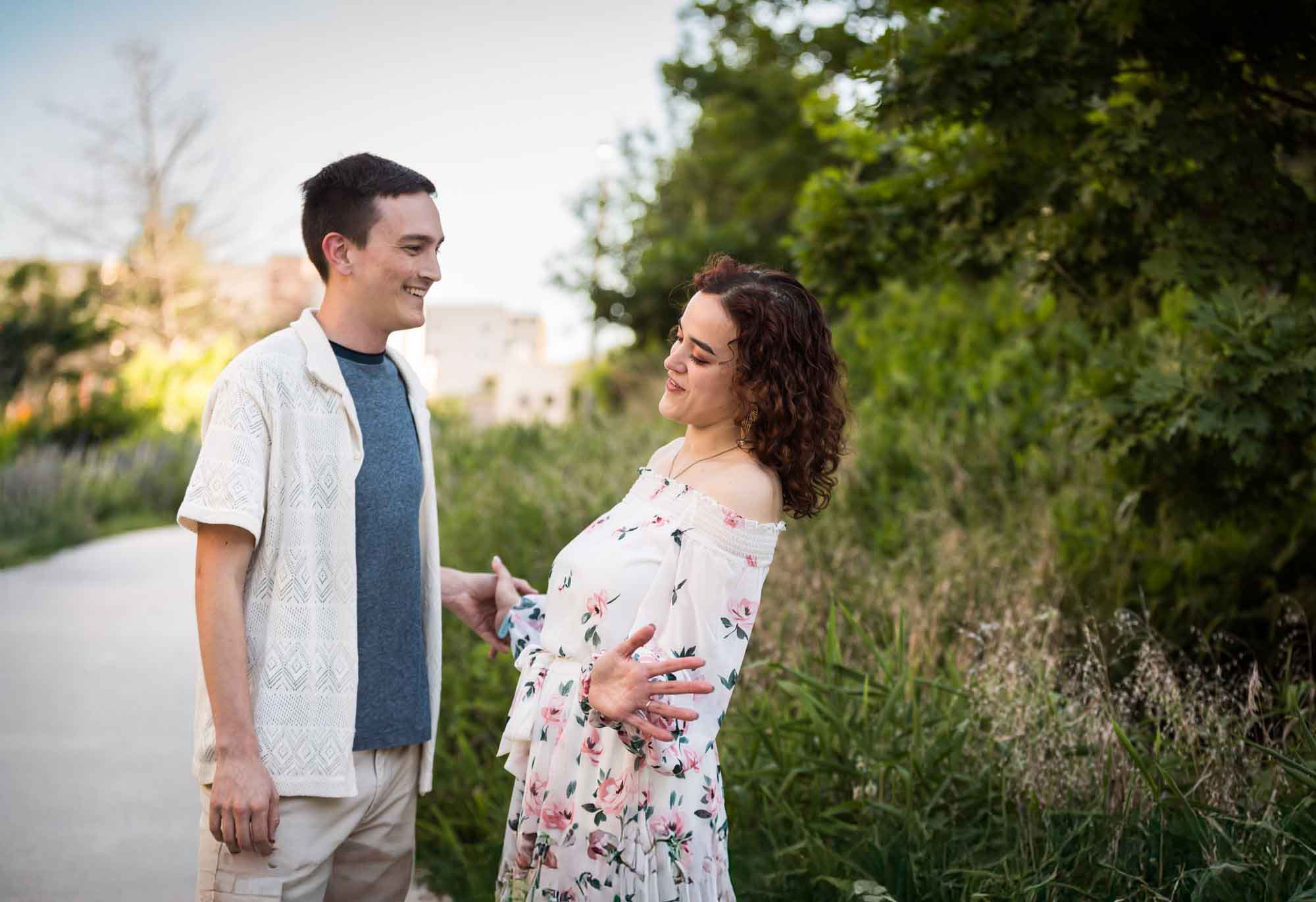 Downtown San Antonio engagement photos of couple talking in middle of pathway in front of green bushes in San Pedro Creek Park