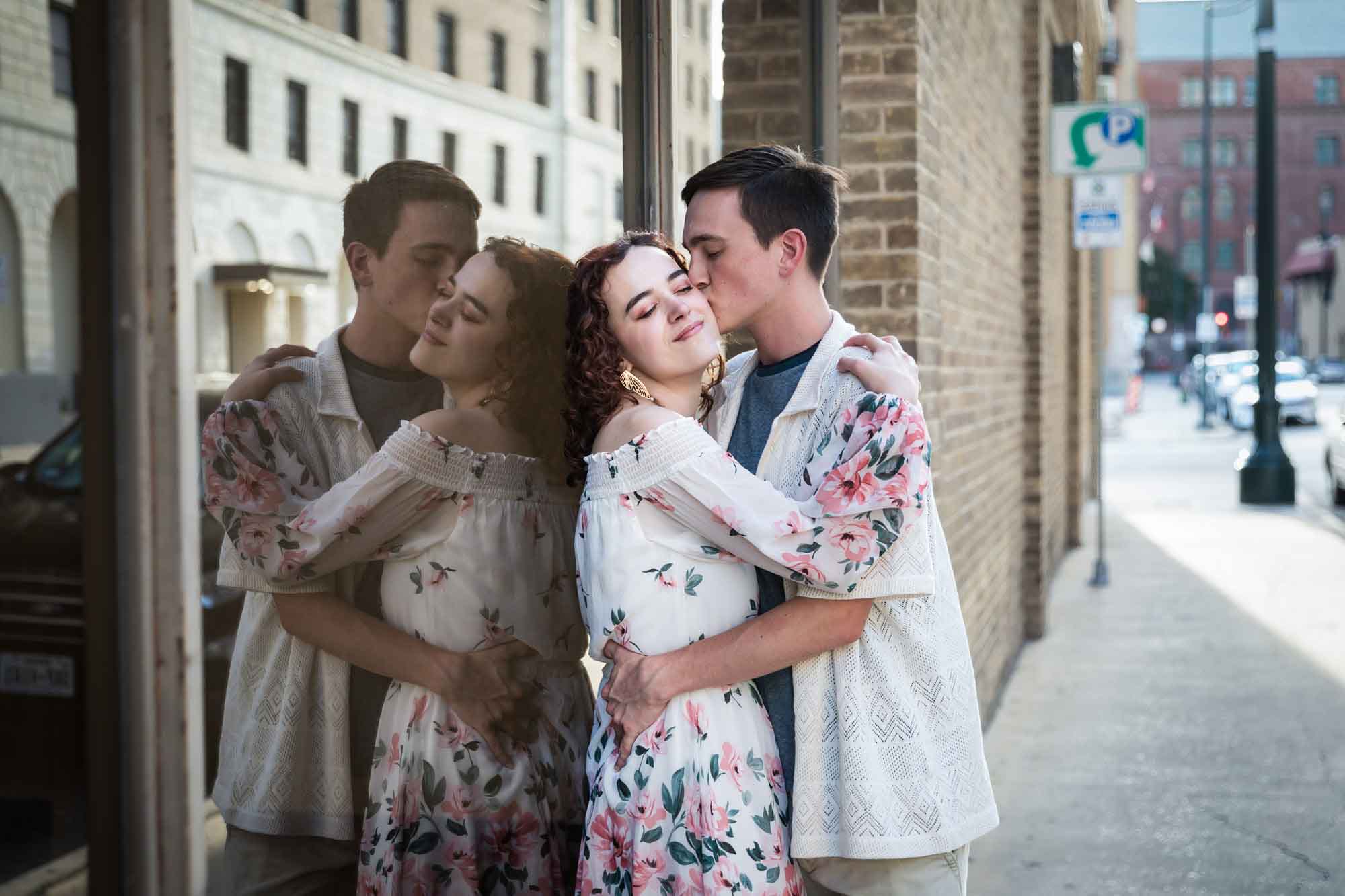 Downtown San Antonio engagement photos of couple kissing on sidewalk leaning against window with reflection