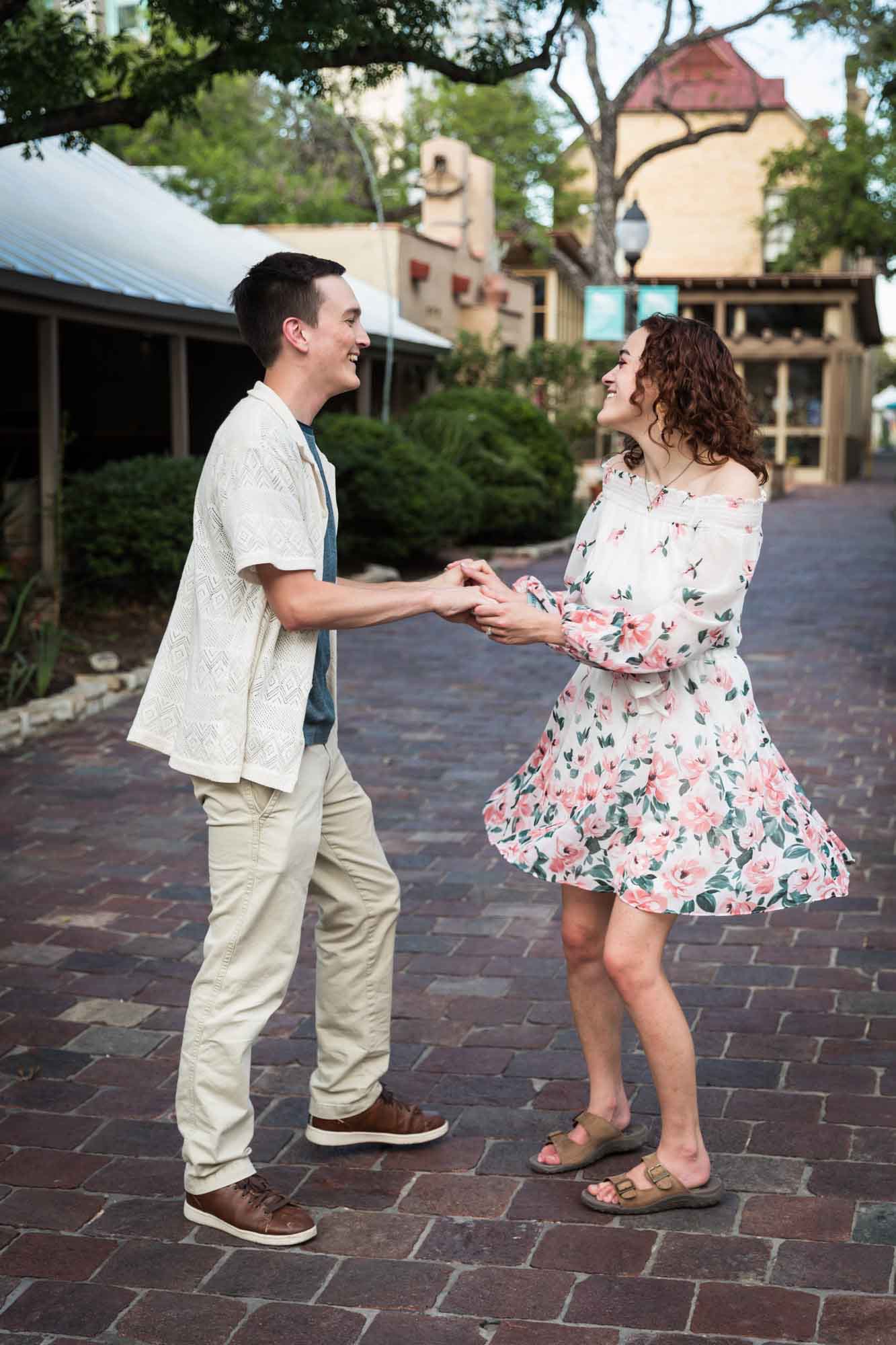 Couple dancing on cobblestone streets at La Villita during downtown San Antonio engagement portrait
