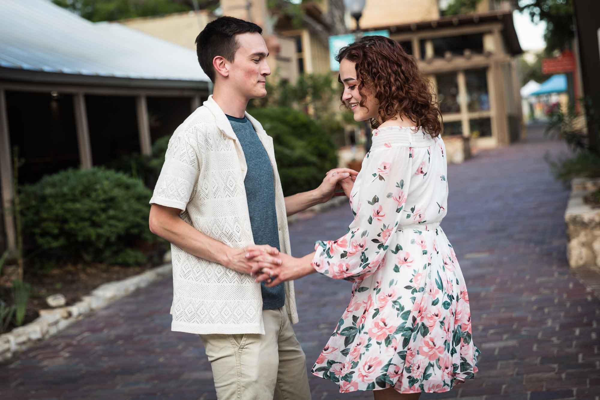 Couple dancing on cobblestone streets at La Villita during downtown San Antonio engagement portrait