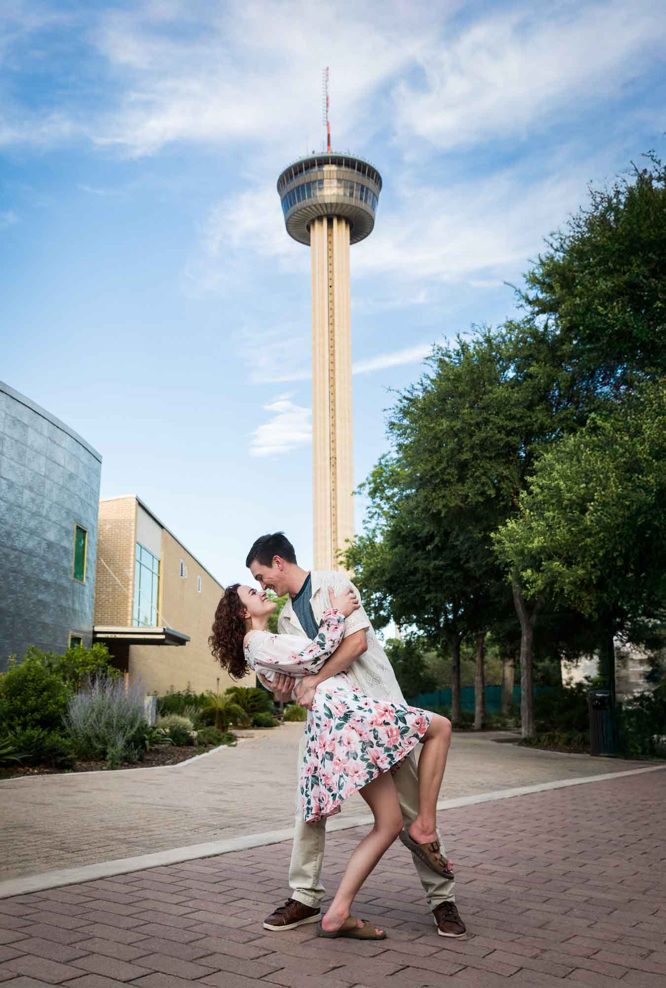 Couple dancing in dip in front of Tower of the Americas at Hemisfair Park during downtown San Antonio engagement portrait