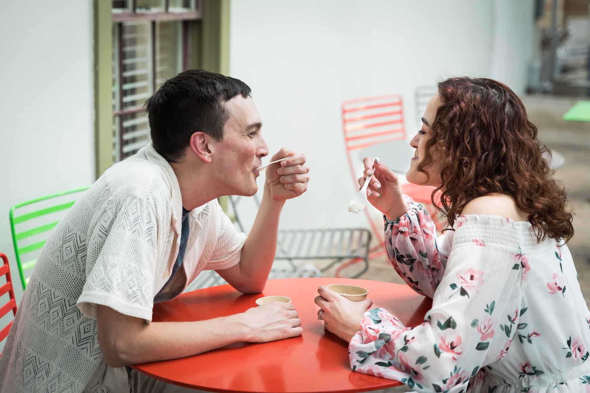 Couple eating ice cream at red table during a downtown San Antonio engagement portrait session