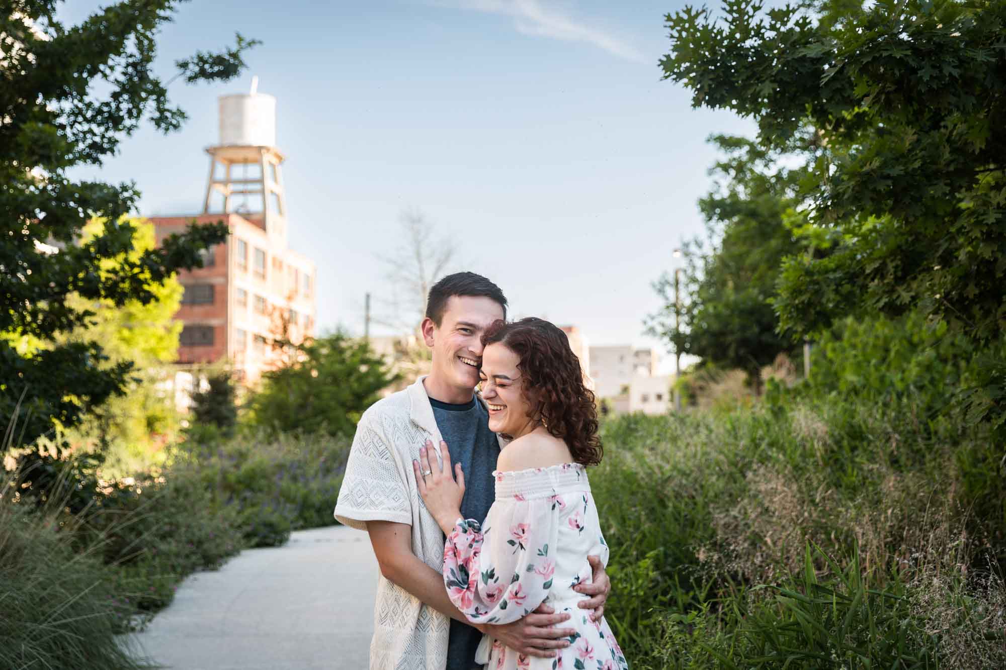 Downtown San Antonio engagement photos of couple hugging in middle of pathway in front of green bushes in San Pedro Creek Park
