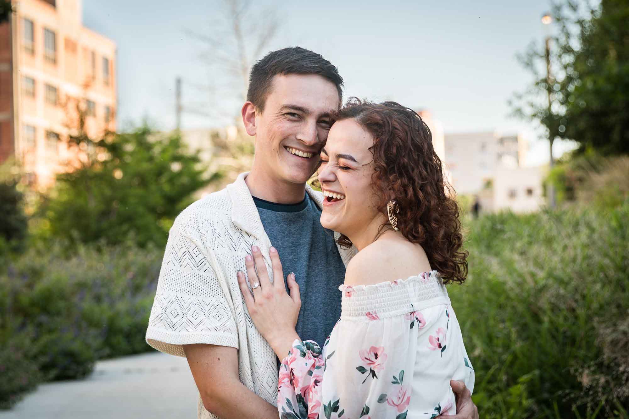Downtown San Antonio engagement photos of couple hugging in middle of pathway in front of green bushes in San Pedro Creek Park