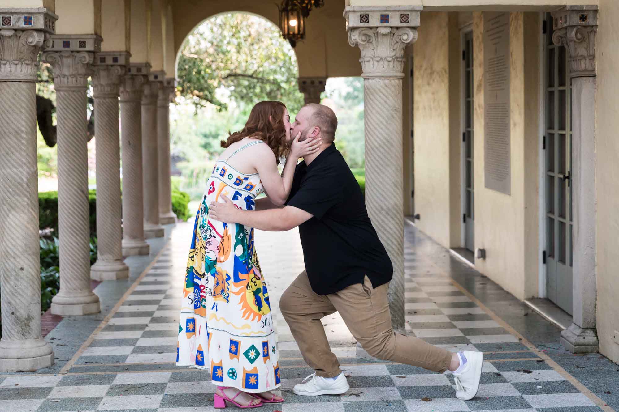 Couple kissing in front of Landa Library colonnade after proposal during a Landa Library surprise proposal