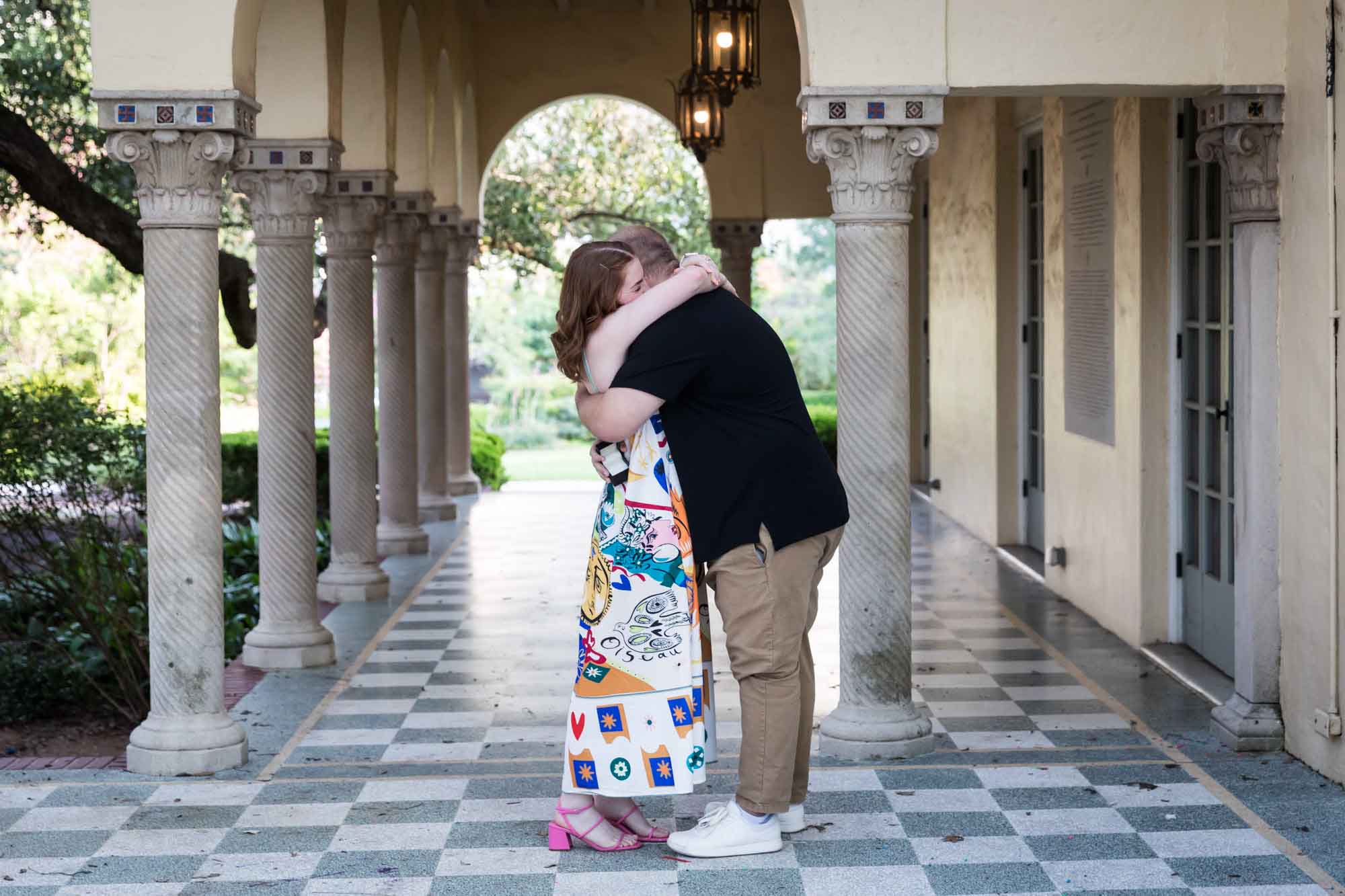 Couple hugging in front of Landa Library colonnade after proposal during a Landa Library surprise proposal