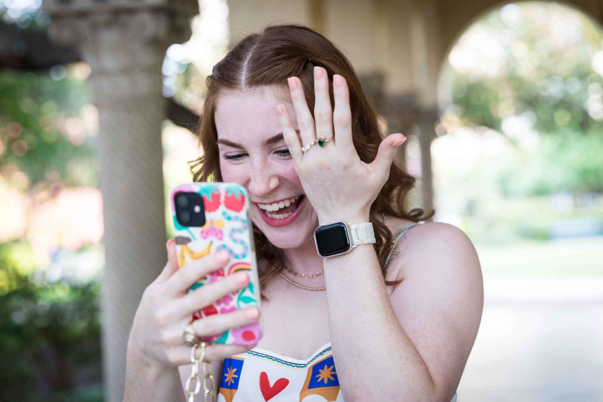 Woman showing hand with engagement ring to cell phone after a Landa Library surprise proposal