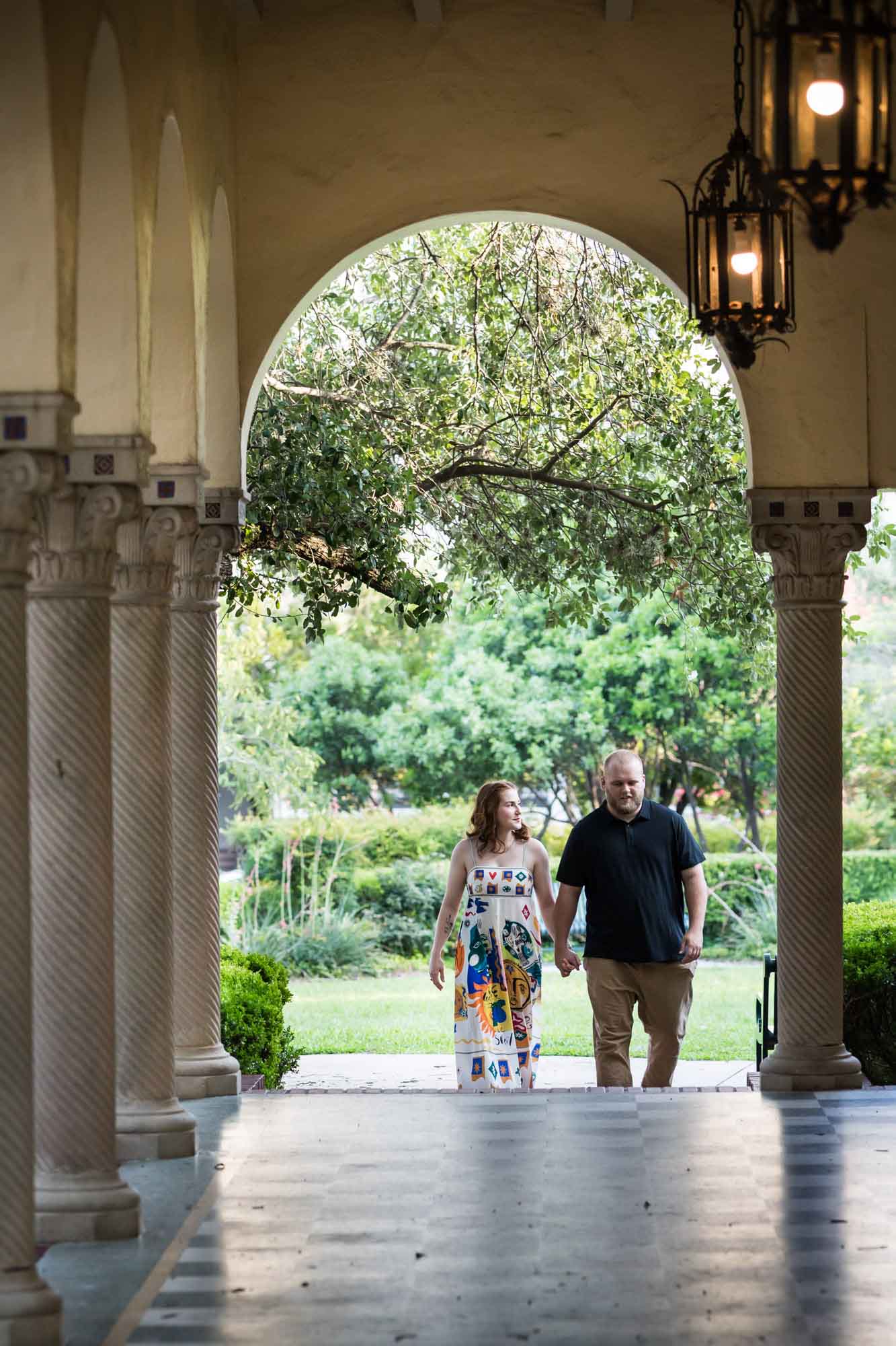 Couple holding hands about to walk through colonnade for an article on how to propose at the Landa Library