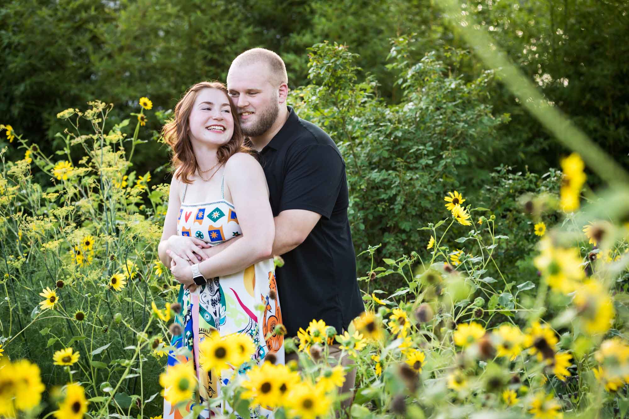 Couple hugging in flower garden of sunflowers during a Landa Library engagement portrait